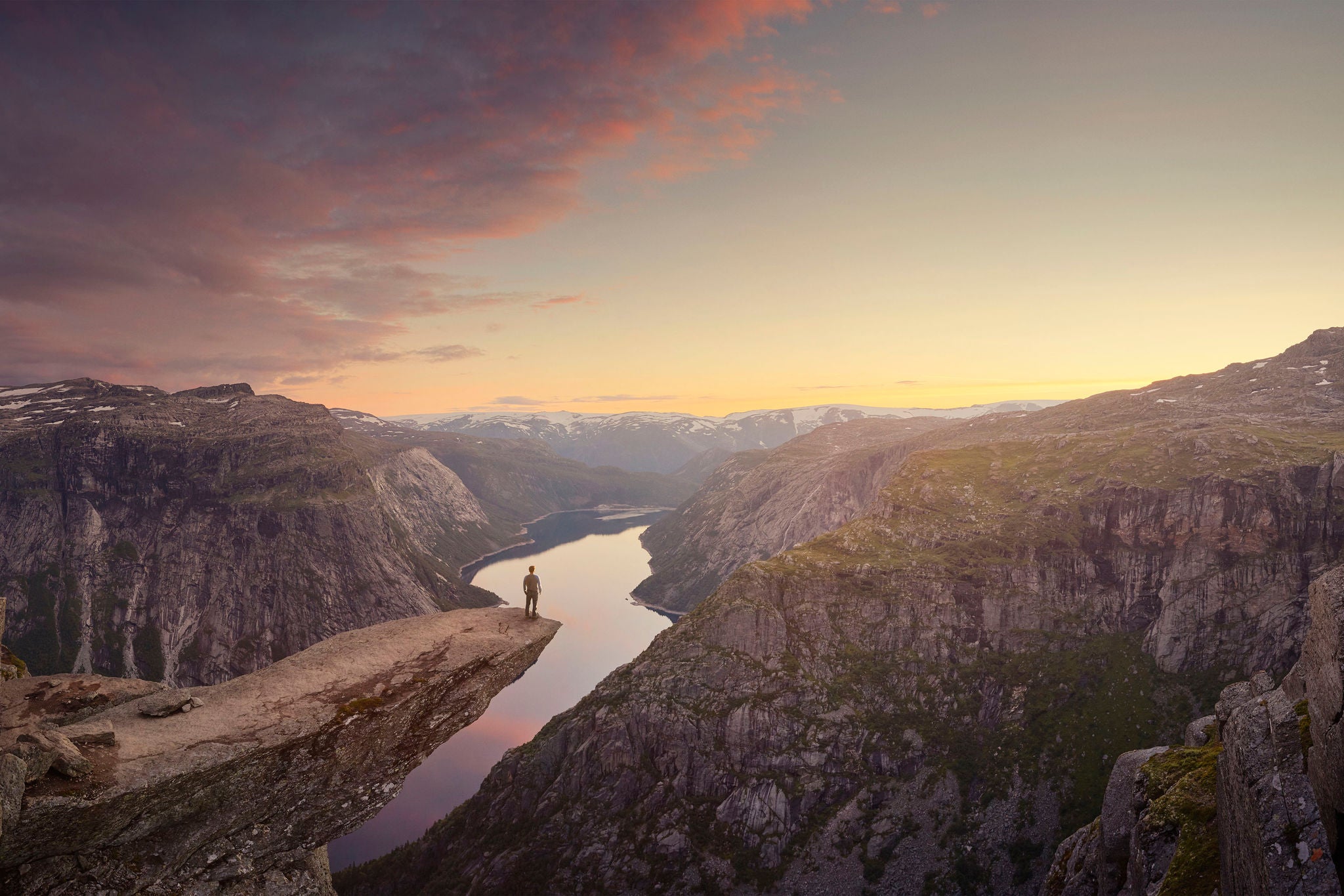 Panoramic of traveller looking out at landscape at sunset, Trolltunga, Norway