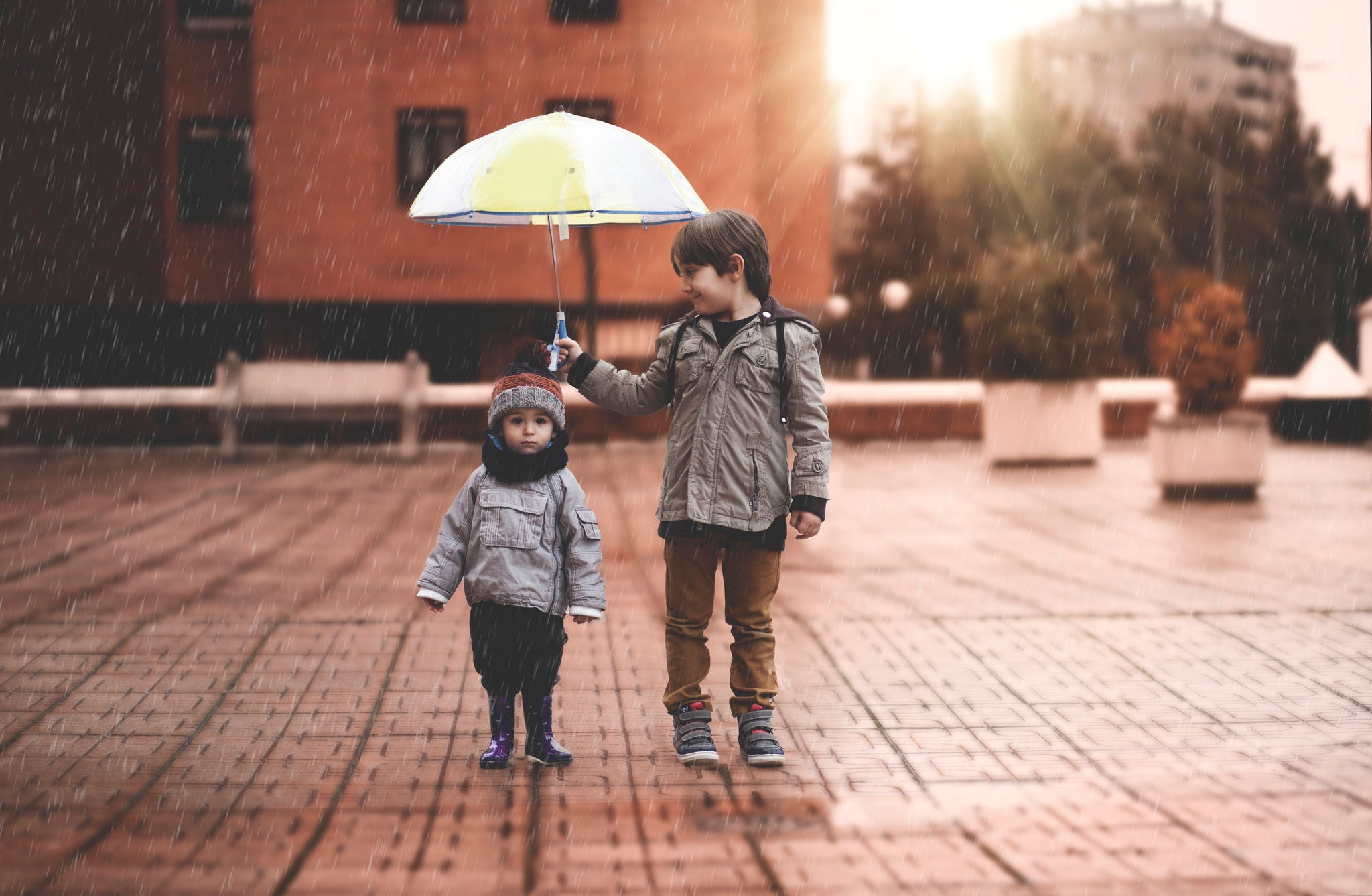 Childrens walking on the street by using umbrella