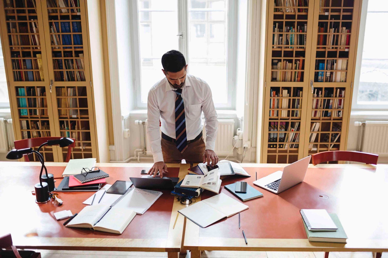 Man researching while standing at table in home library