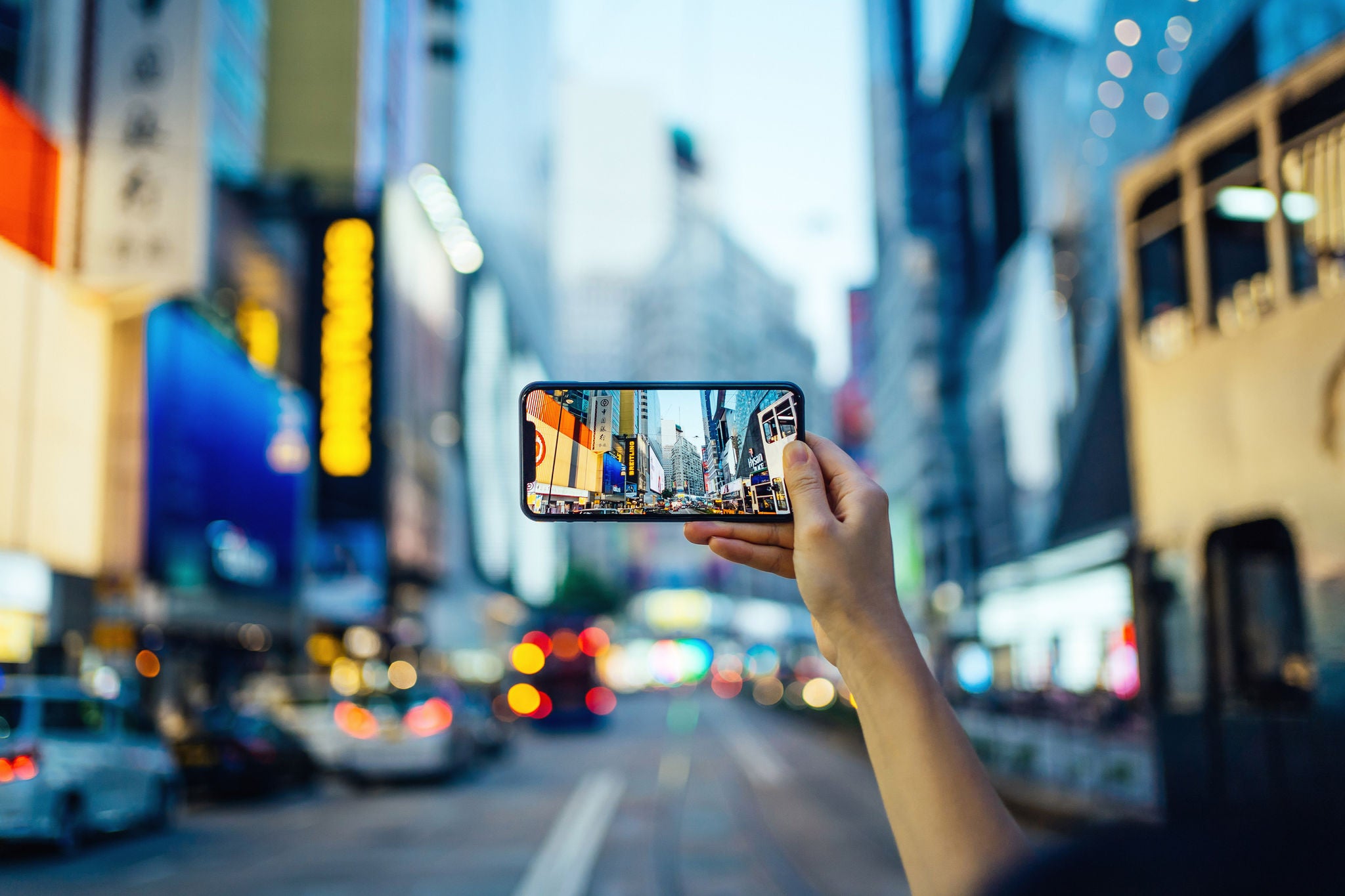 Woman taking photo with smartphone in busy downtown