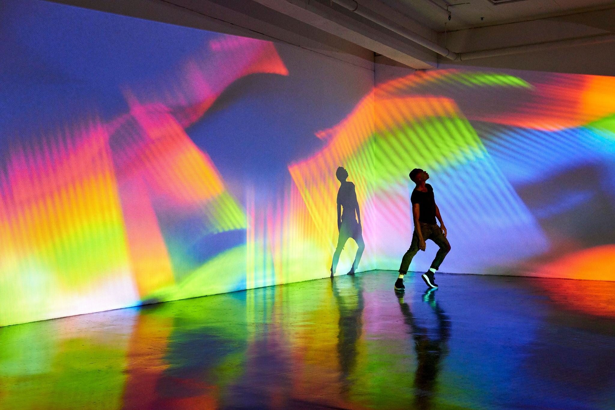 Man dancing in front of large scale abstract image being projected onto the walls behind him