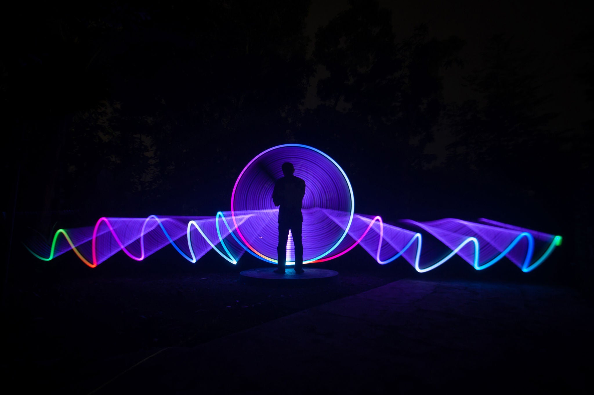 One person standing alone against a Colorful circle light painting as the backdrop