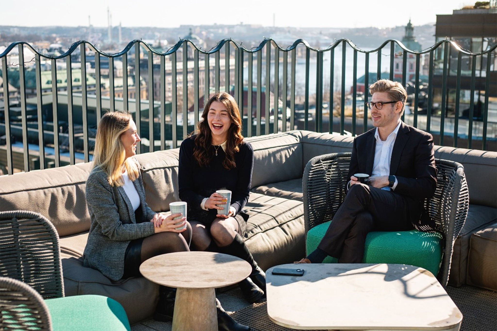 Tre kollegor tar en kaffepaus på takterassen