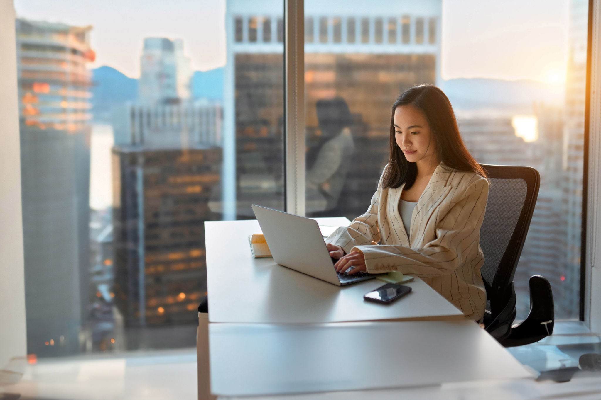 Young busy Asian business woman executive working on laptop in corporate office.