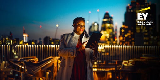 Businesswoman using digital tablet against London cityscape at night