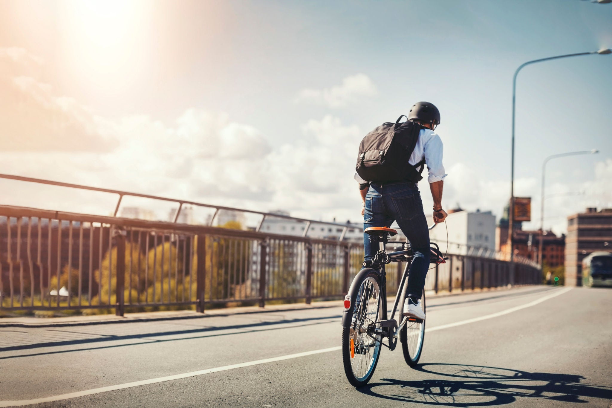  Bakifrån av affärsman som cyklar på bro i staden