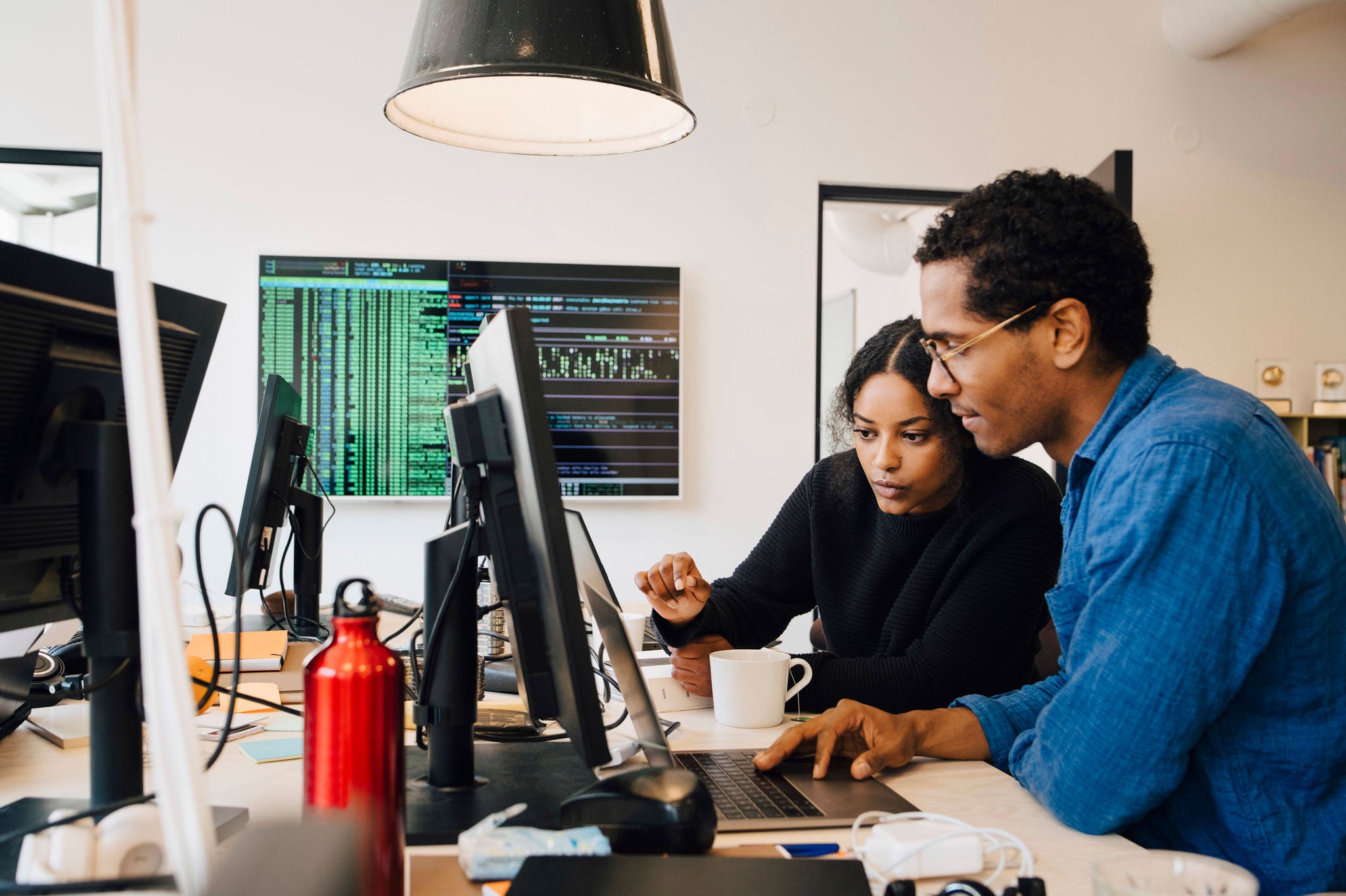 ey-focused-male-and-female-engineers-coding-over-laptop-on-desk-in-office