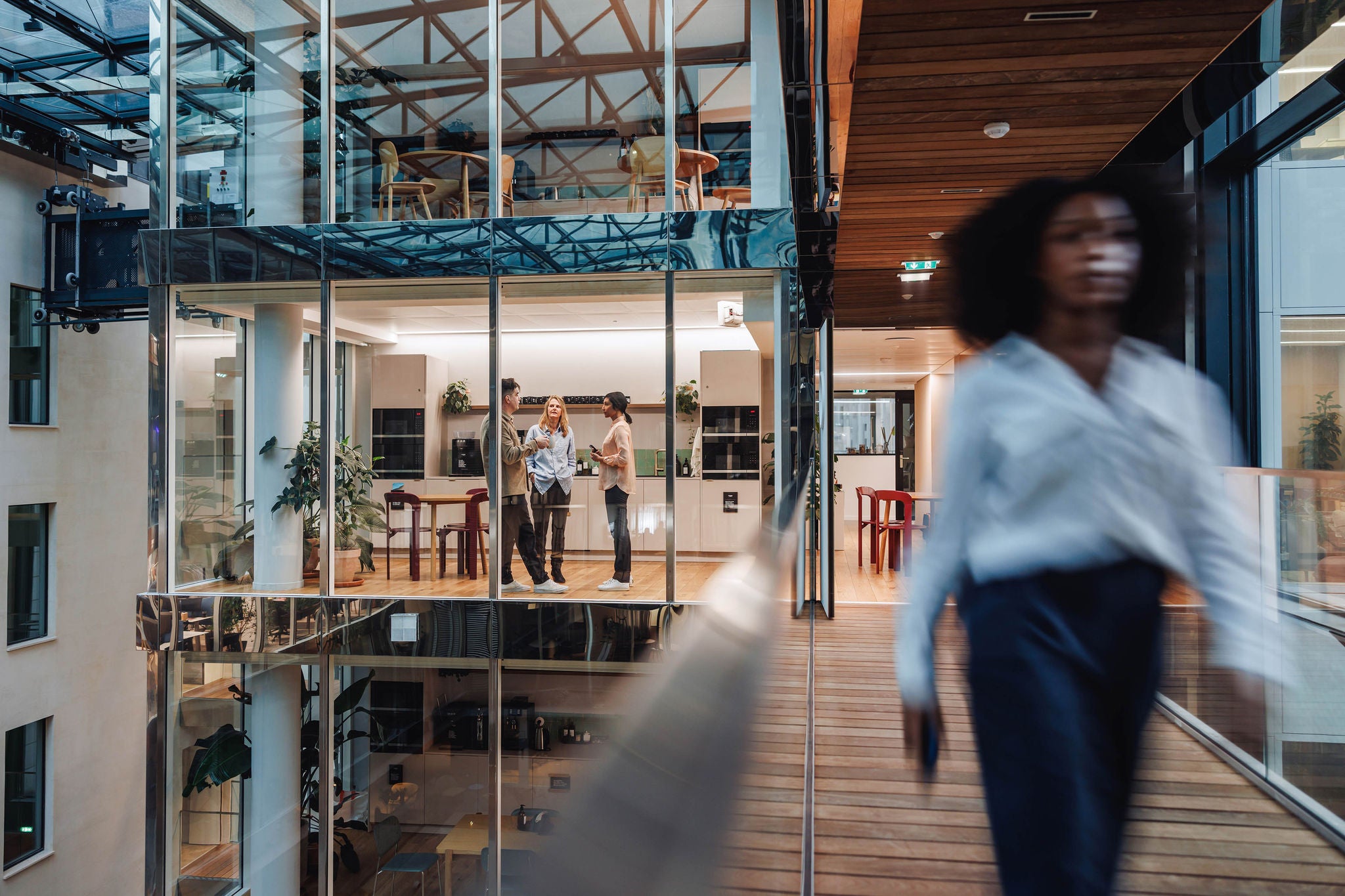 A group of diverse business professionals engage in a discussion inside a well-lit modern office cafe, exemplifying collaboration in an informal setting