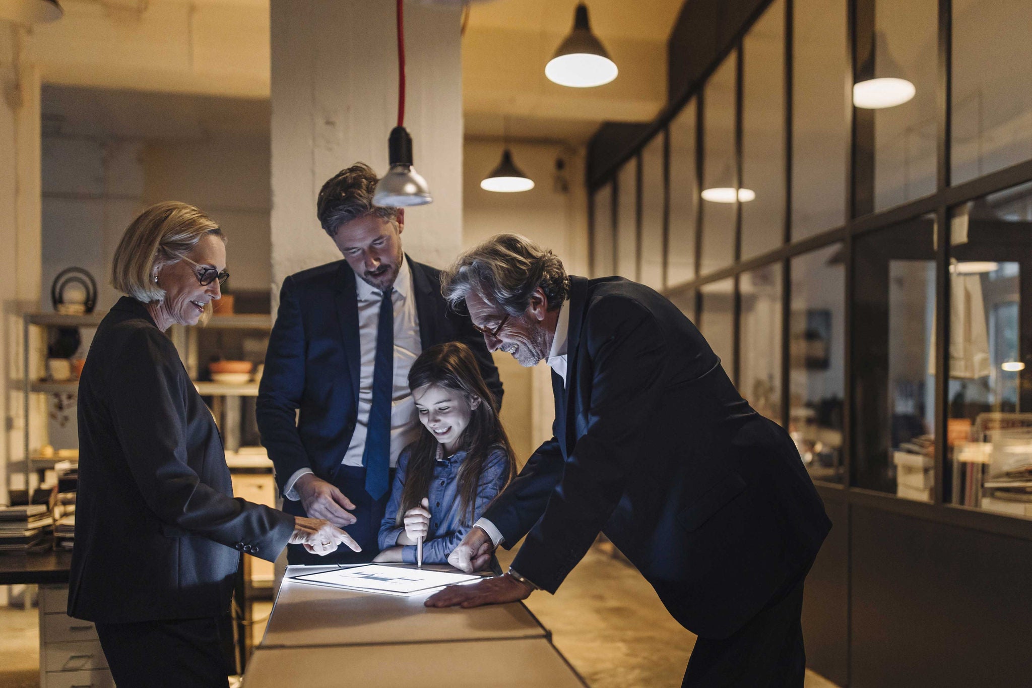 Business people and girl looking at shining tablet in office 