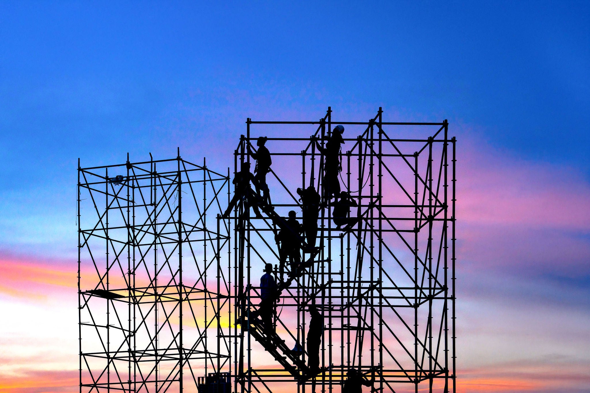 Engineers silhouetted on scaffolding at dusk