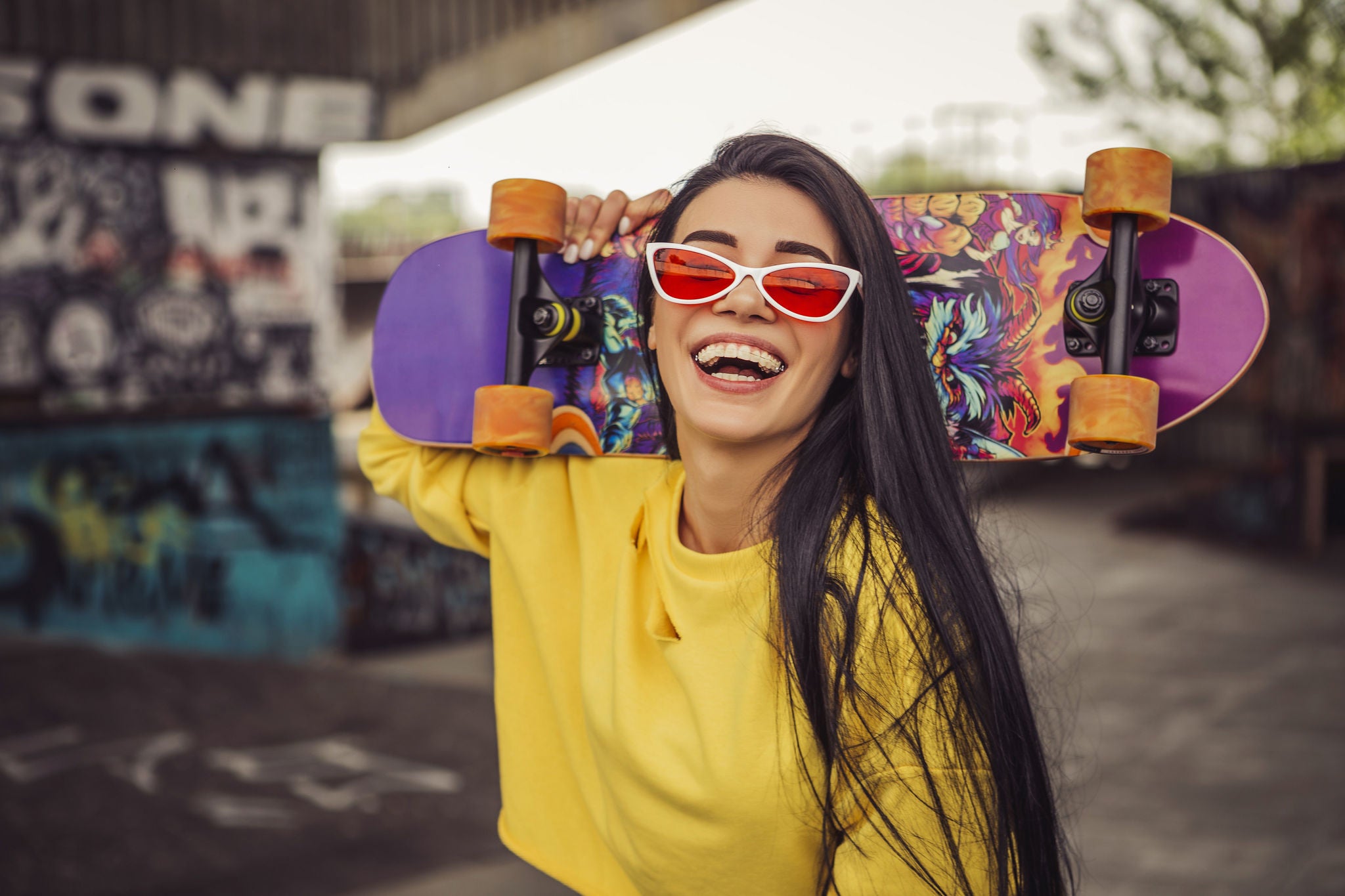 Sexy slim fit brunette woman in sport casual outfit in a skate park. Active leisure on a longboard