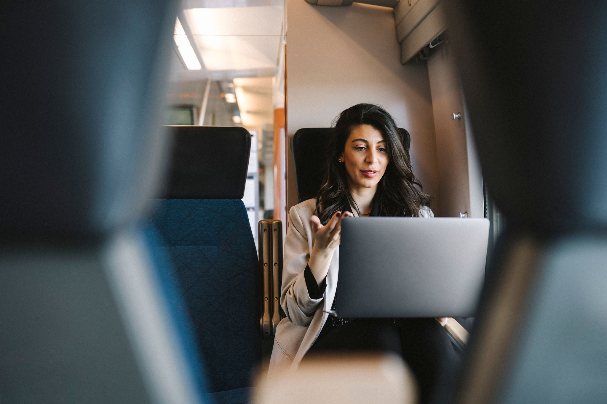 portrait of young woman talking on her laptop sitting on a train