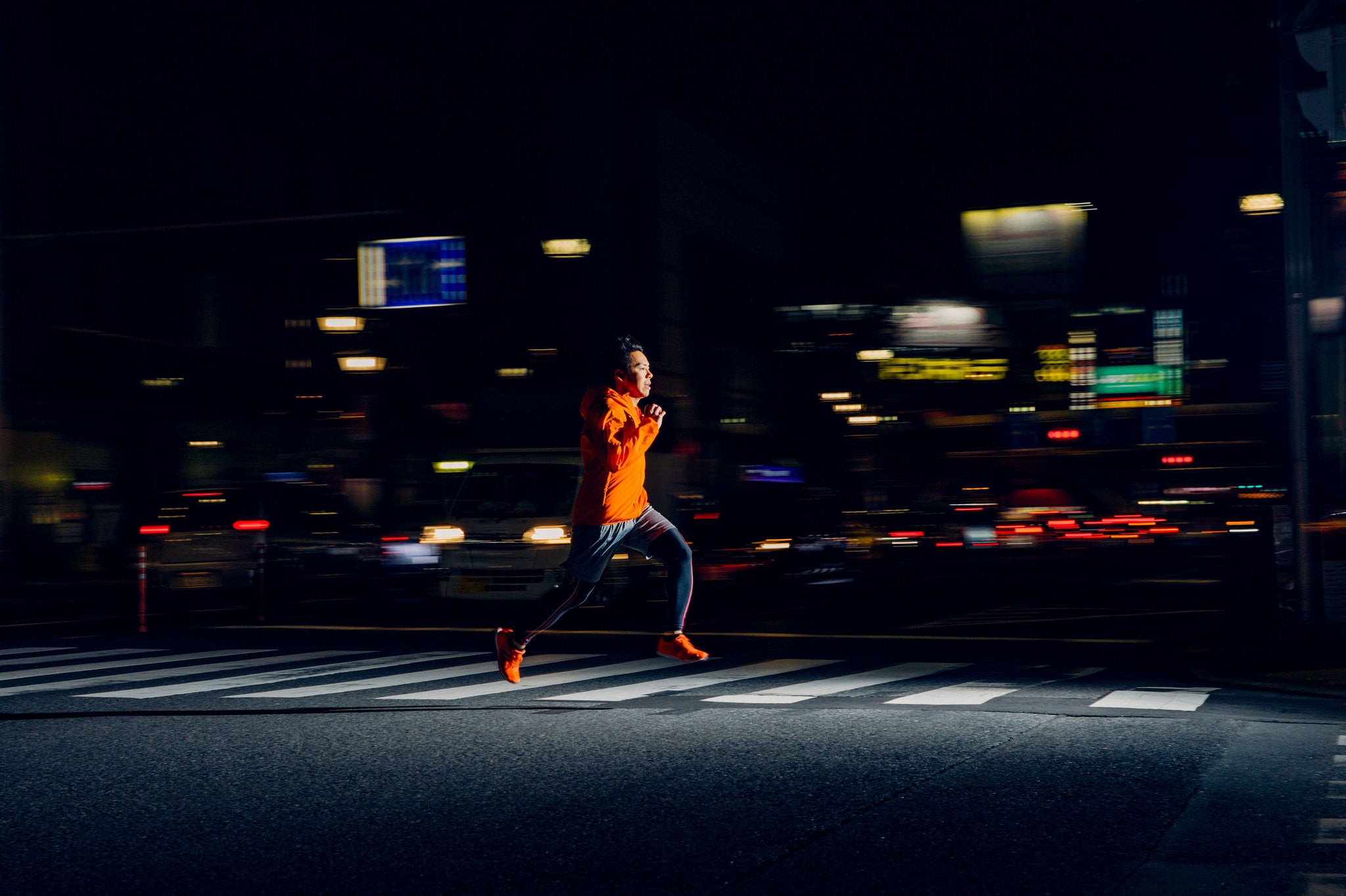 He is wearing running clothing and speeds through the streets as he loves to stay healthy and in top fitness while in the city. Image taken in Tokyo, Japan.