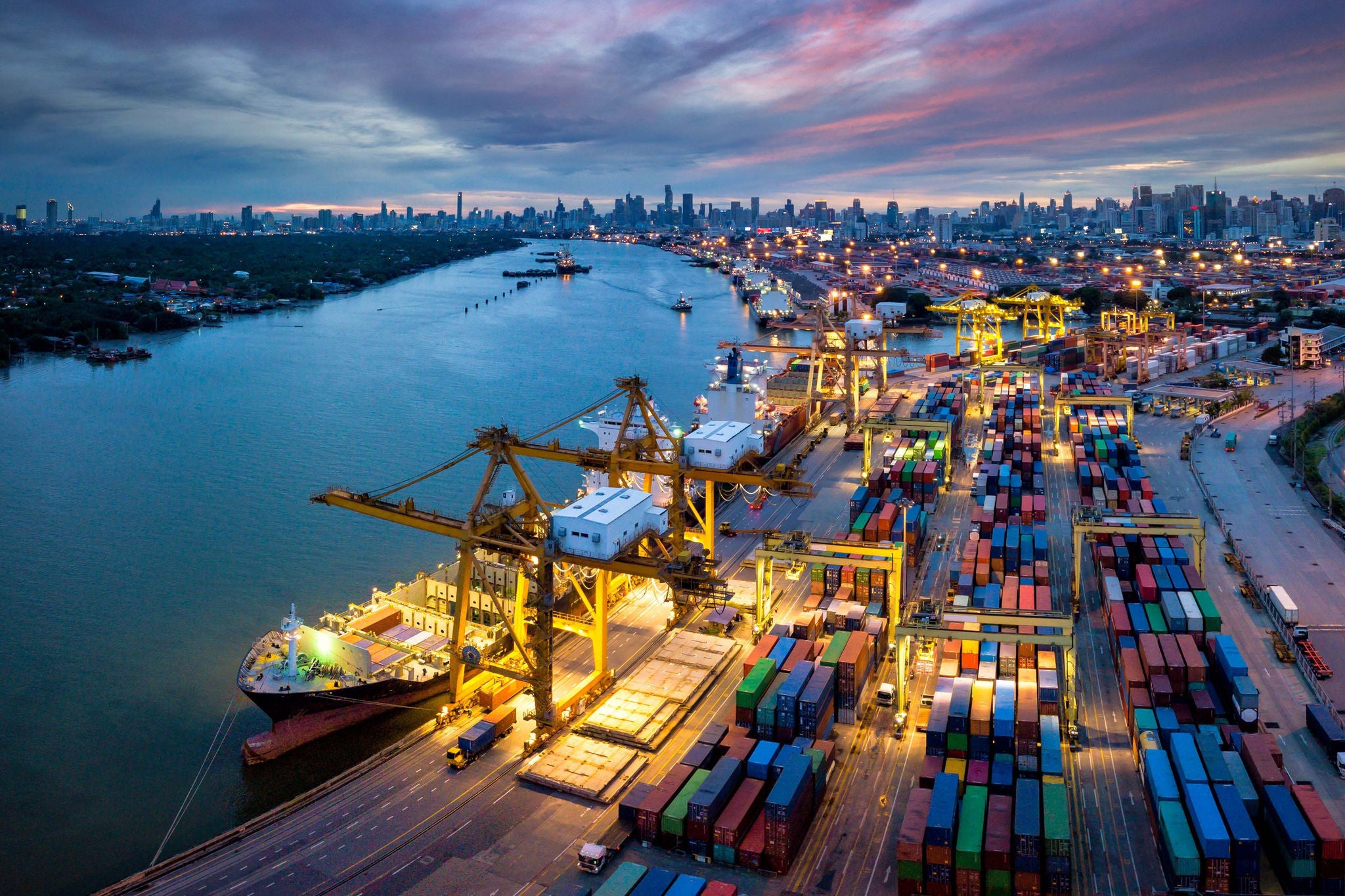 Moderner Containerhafen mit Kränen, Containerschiffen und beleuchteter Skyline a