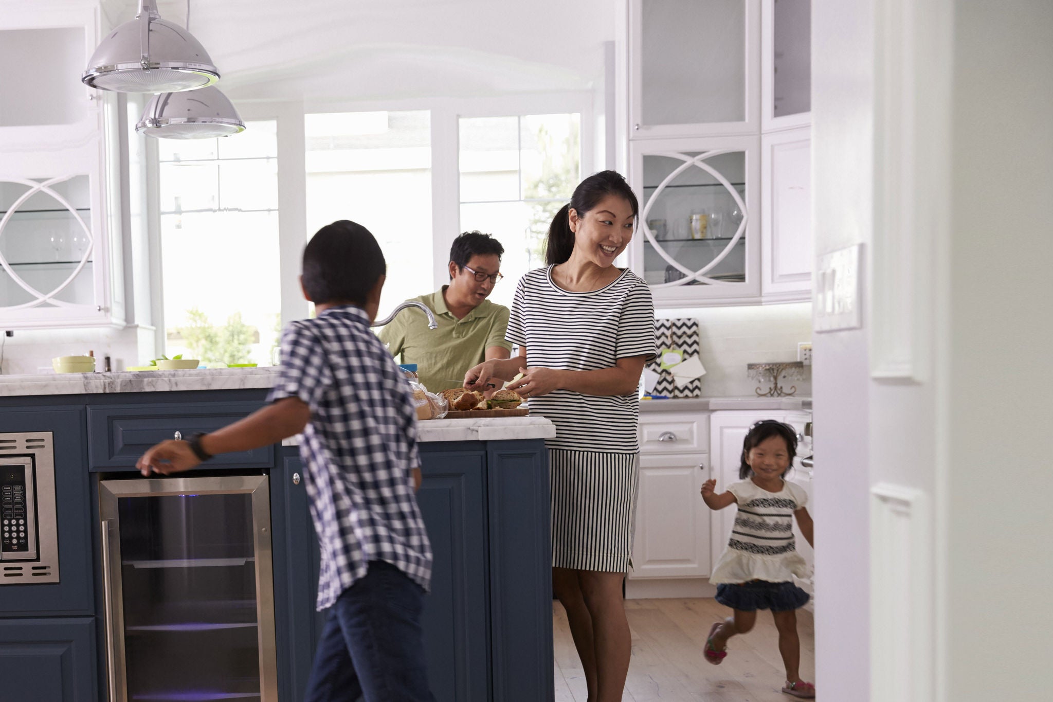 Parents prepare food as children play in kitchen