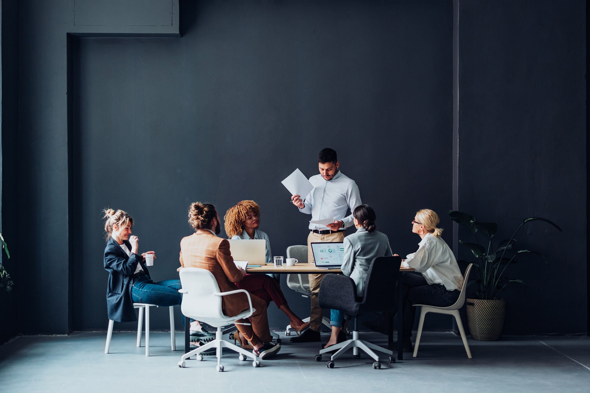 Multi ethnic team of six happy businessman and businesswoman discussing ideas together during a casual meeting at the office.