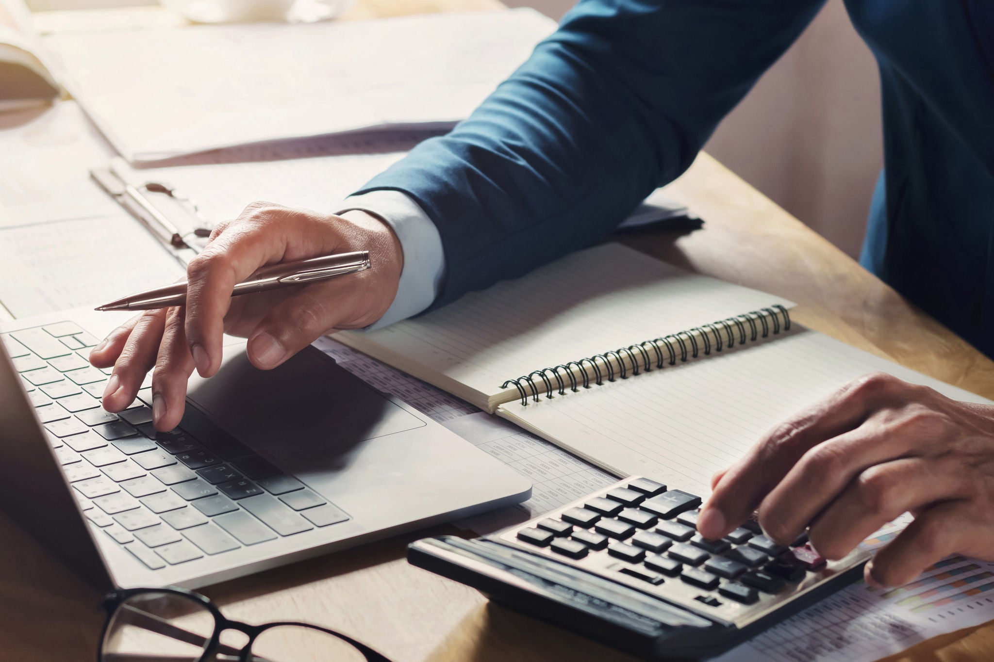 Geschäftsmann arbeitet mit Notebook und Taschenrechner