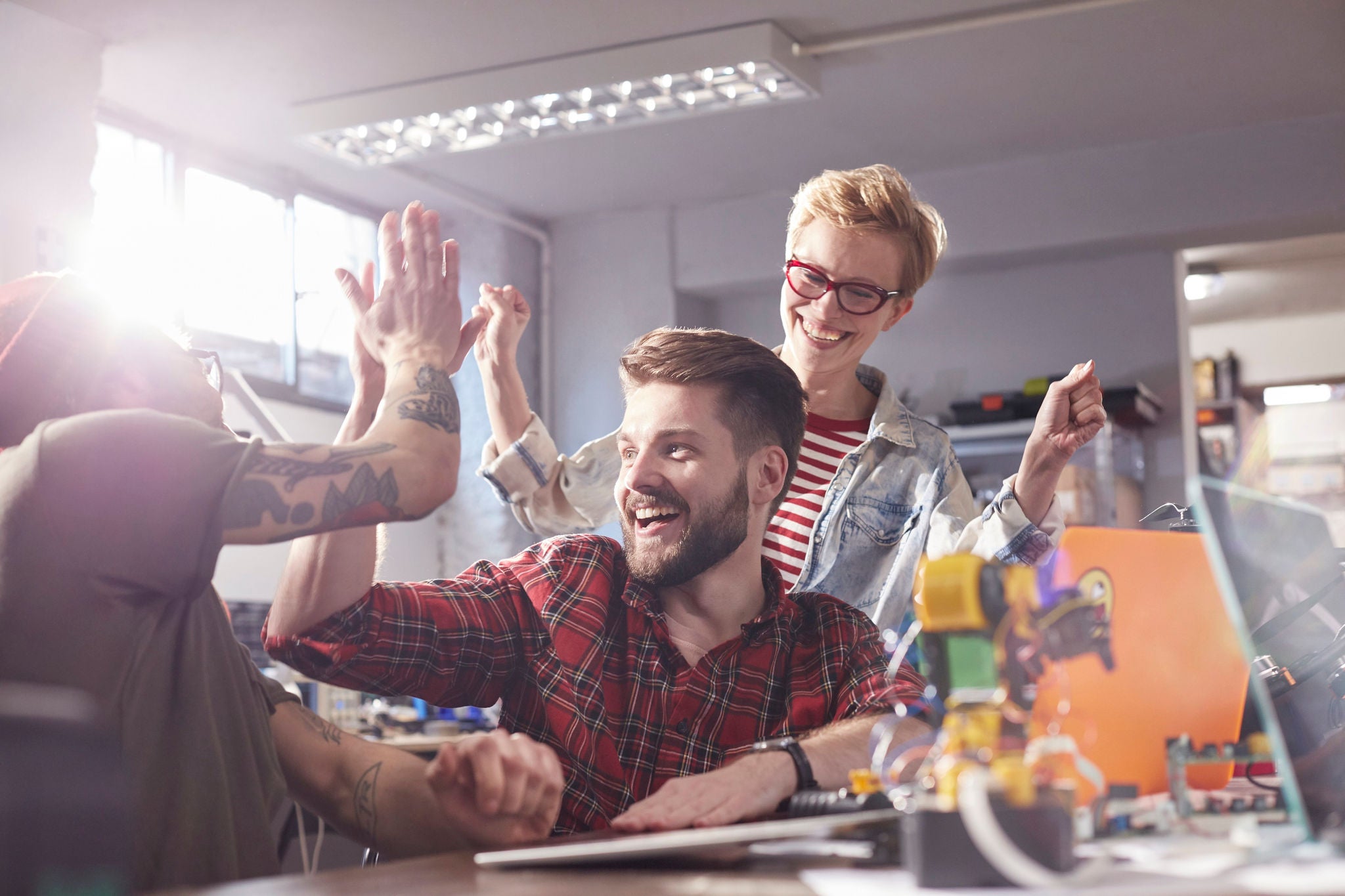 Enthusiastic Designers Highfiving Celebrating In Workshop