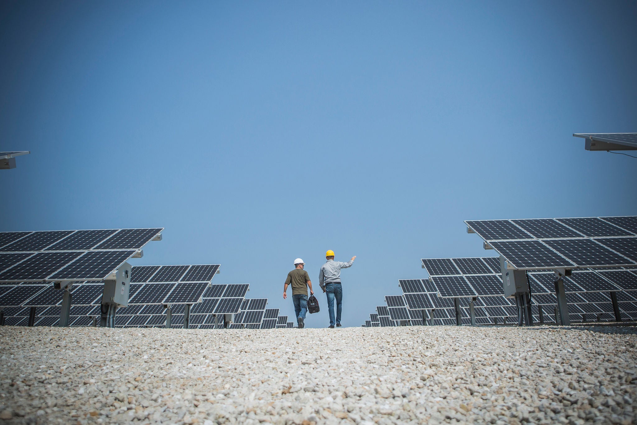 Dos técnicos caminando entre paneles solares por la mañana