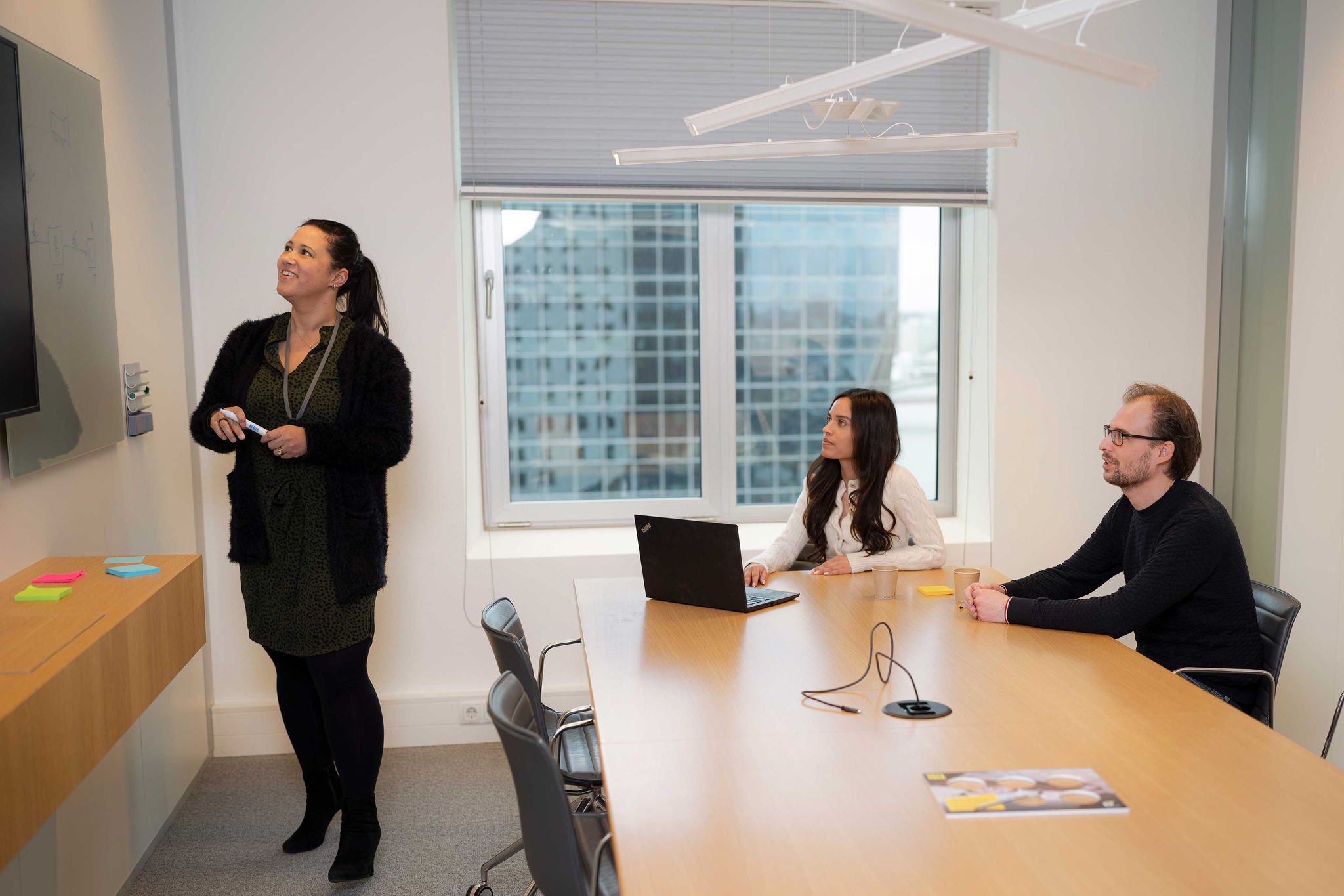 A lady is explaing  infront of two employee