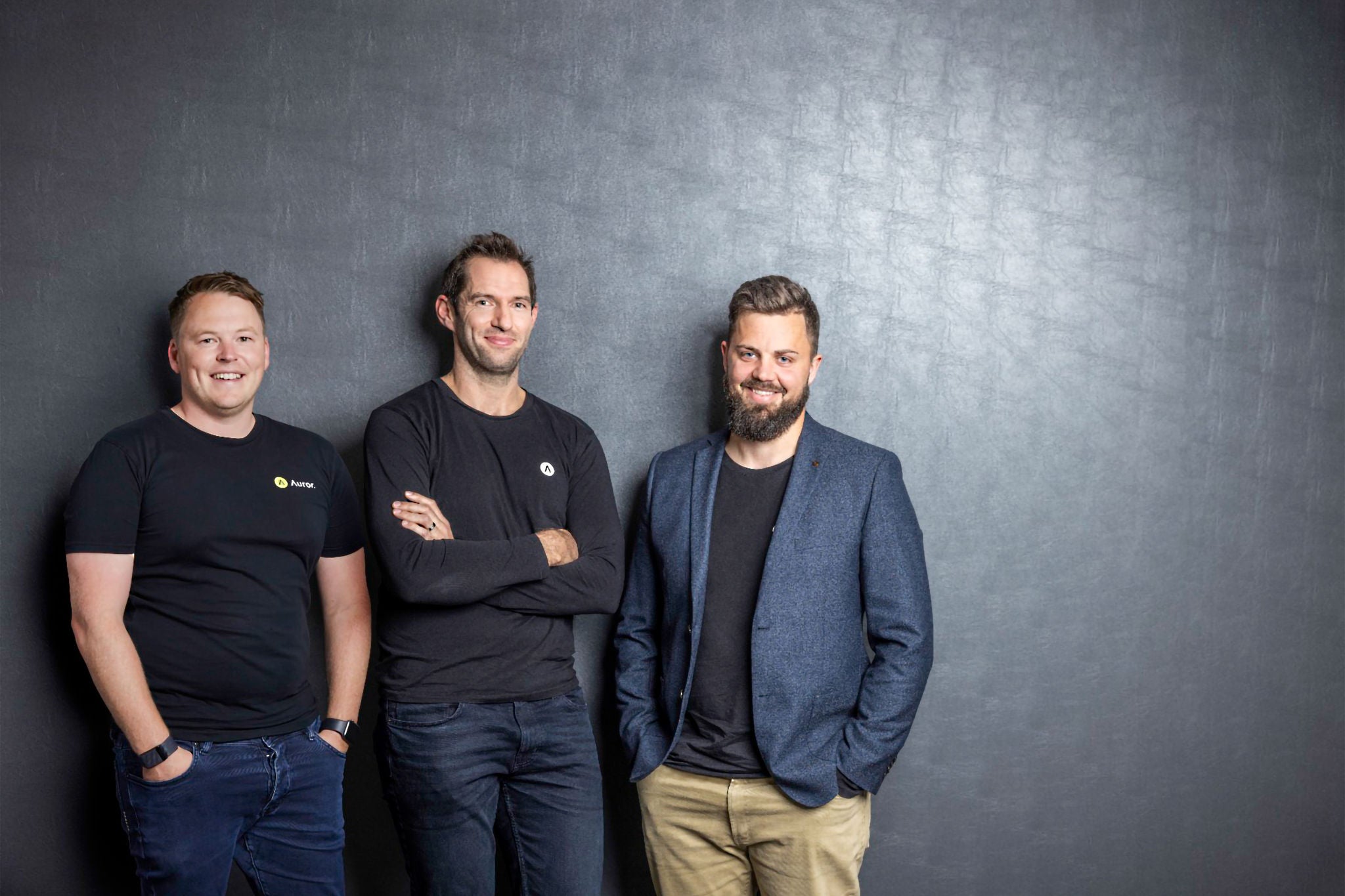 Ey Three businessman standing in front of black wall