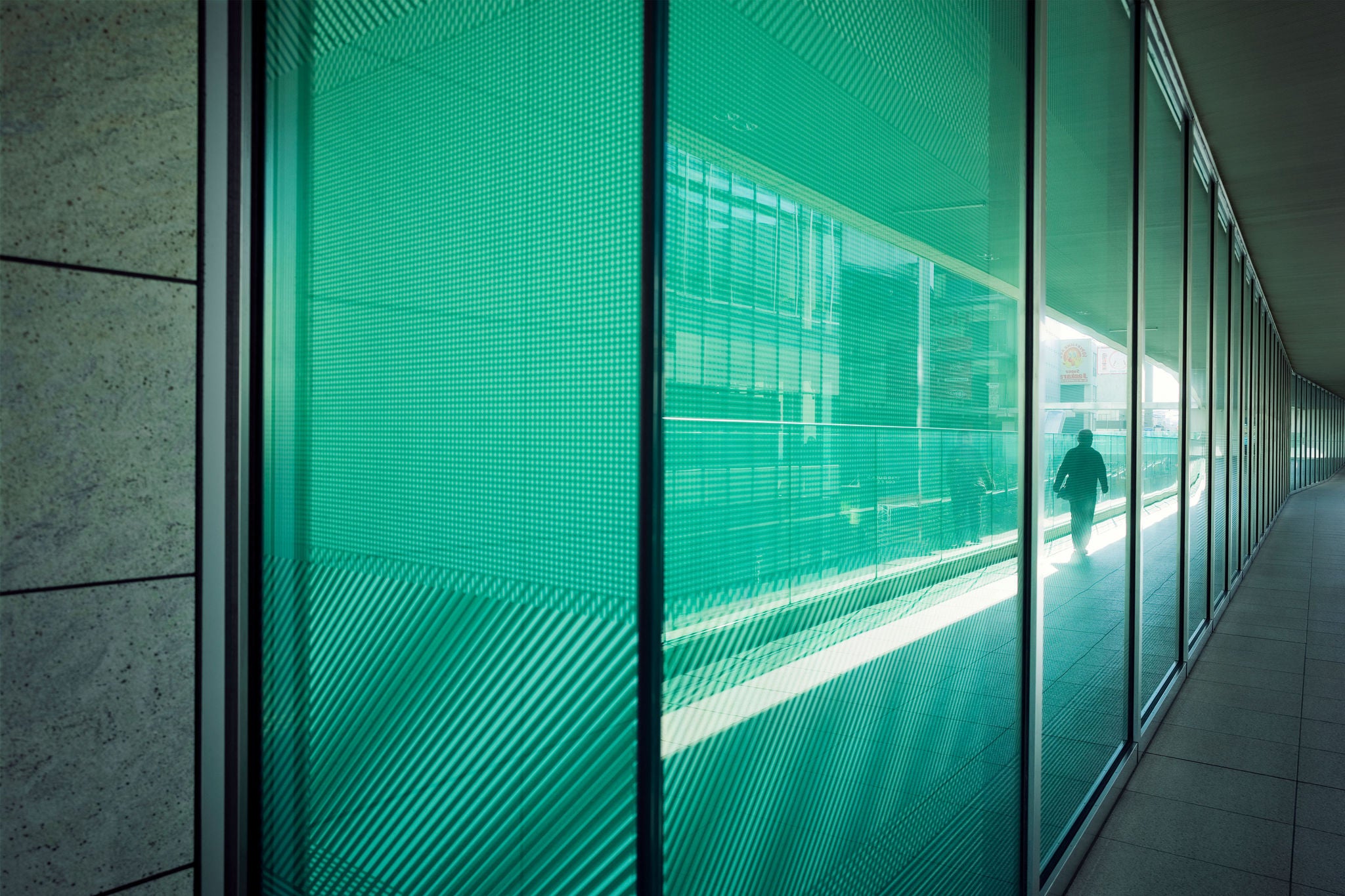Colourful green glass facade of building reflecting city life