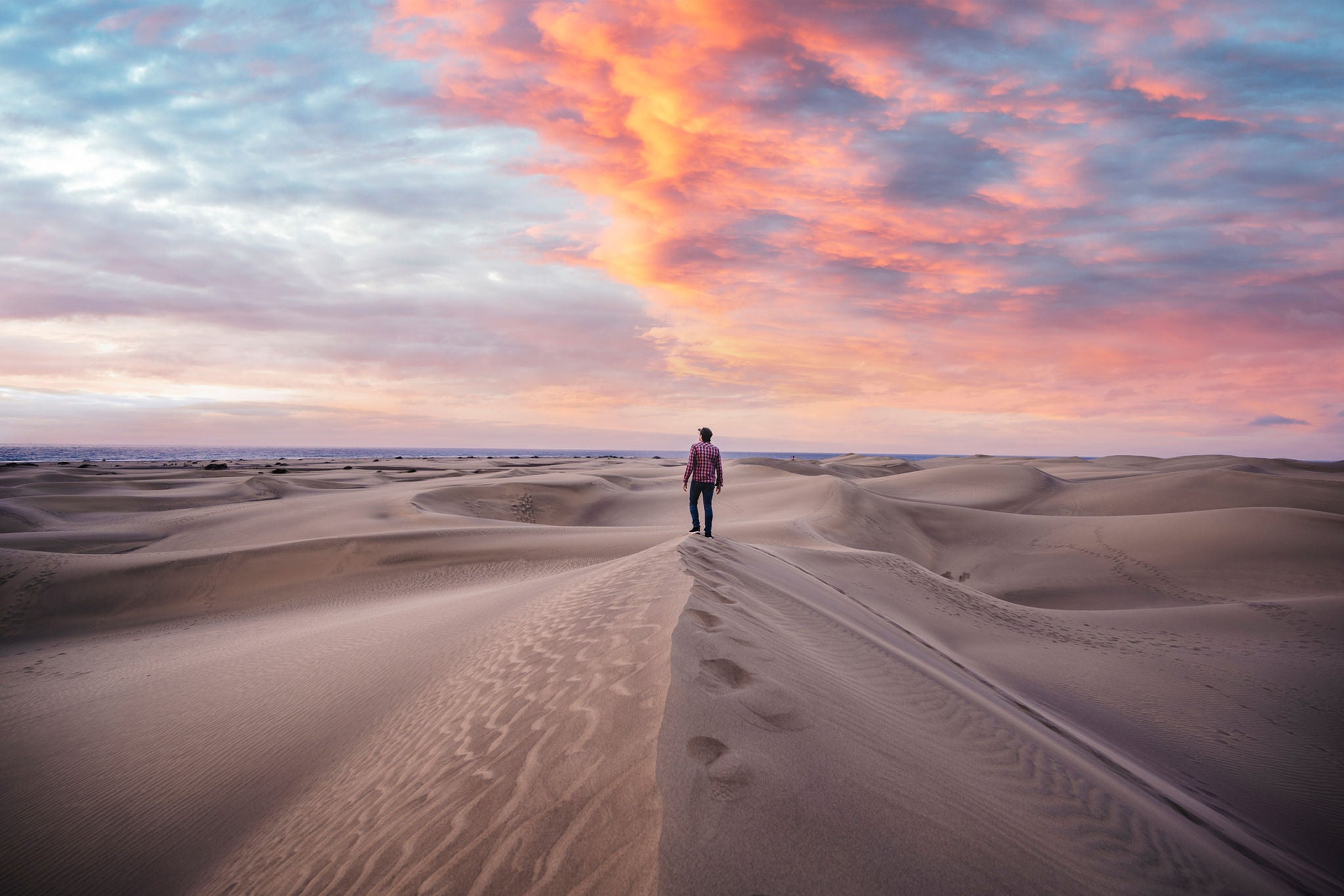 man standing on top of sand dune