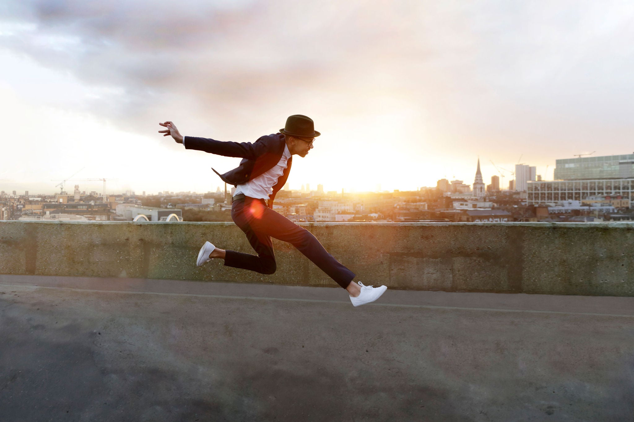 ey-young-man-in-hat-leaping-on-city-rooftop-static