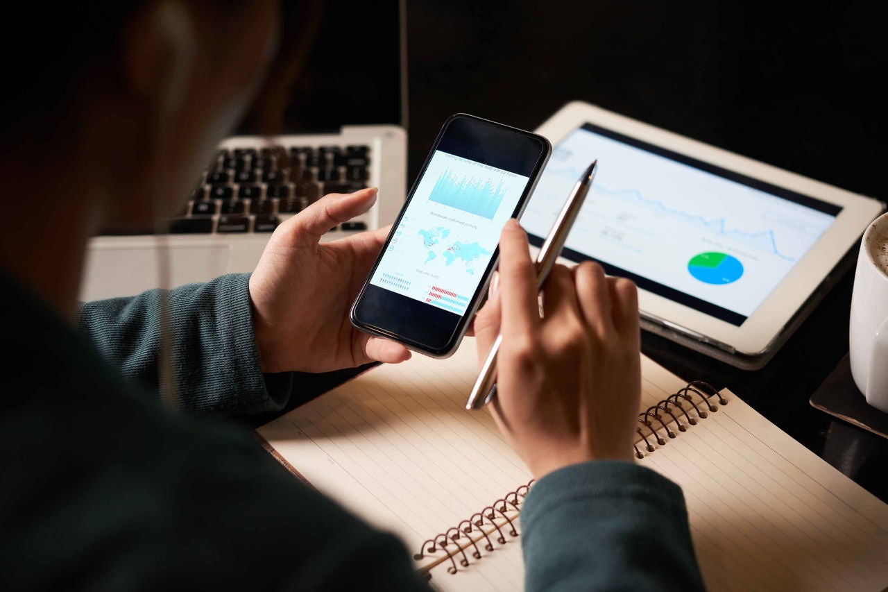 Hands of business lady analyzing diagrams on smartphone and tablet computer