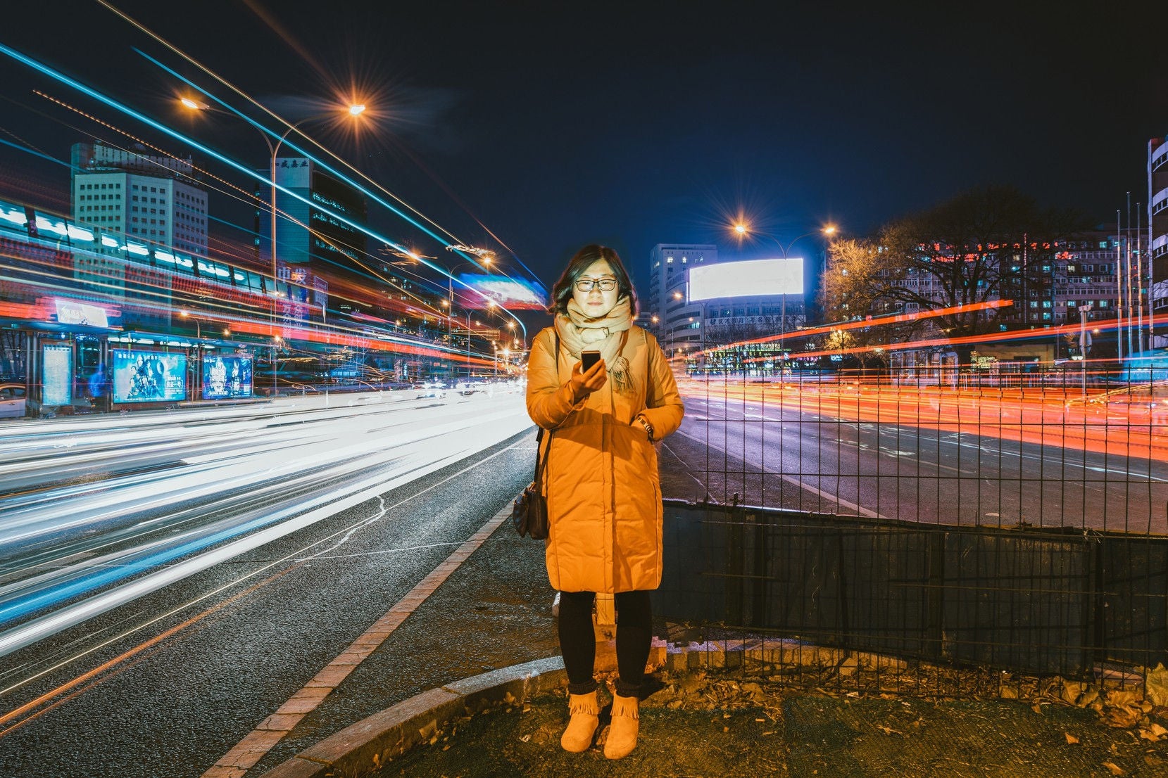 Woman looking into the phone by standing aside on road