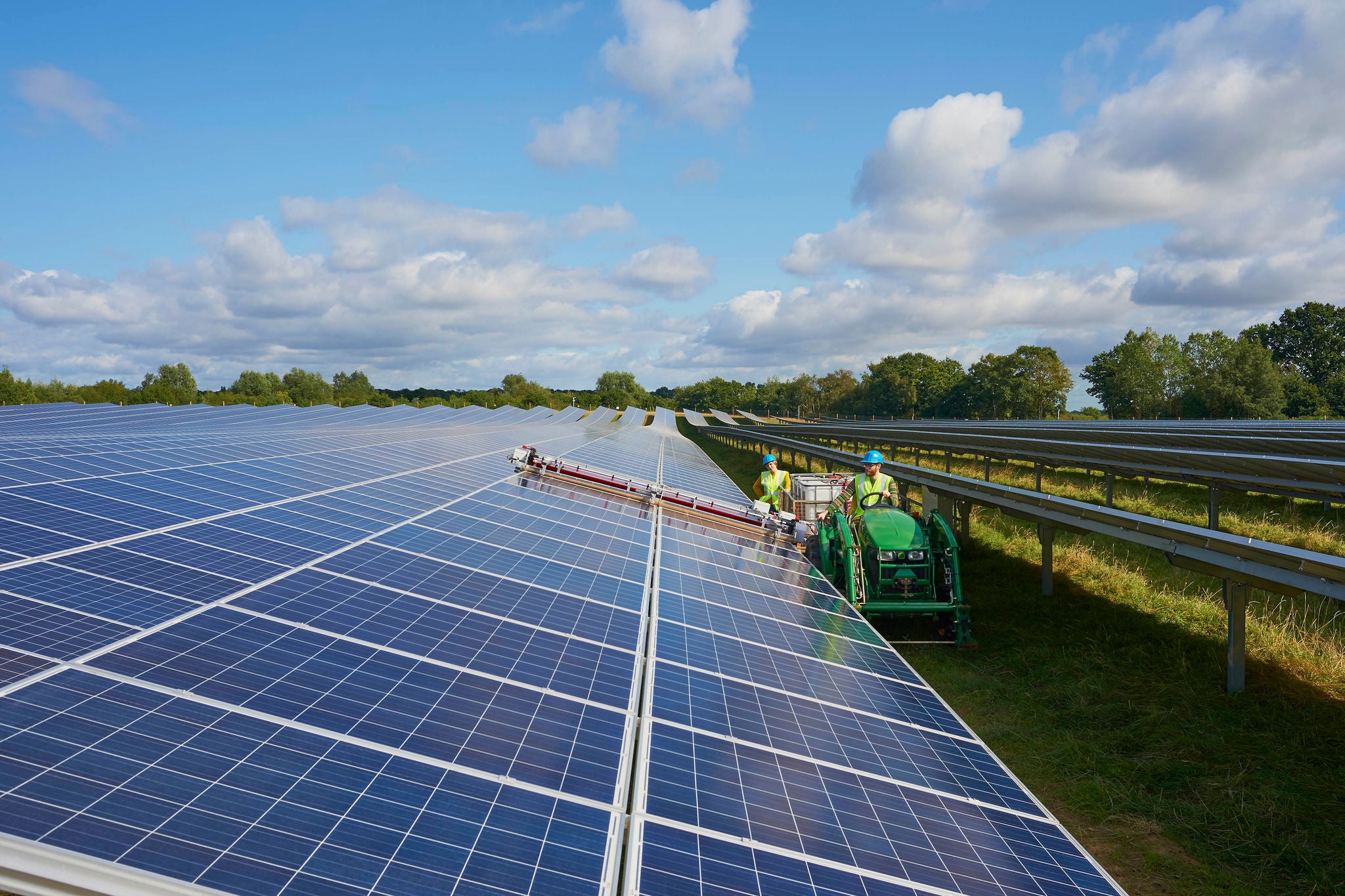 Young farmers using machinery to clean the solar panels in their farm