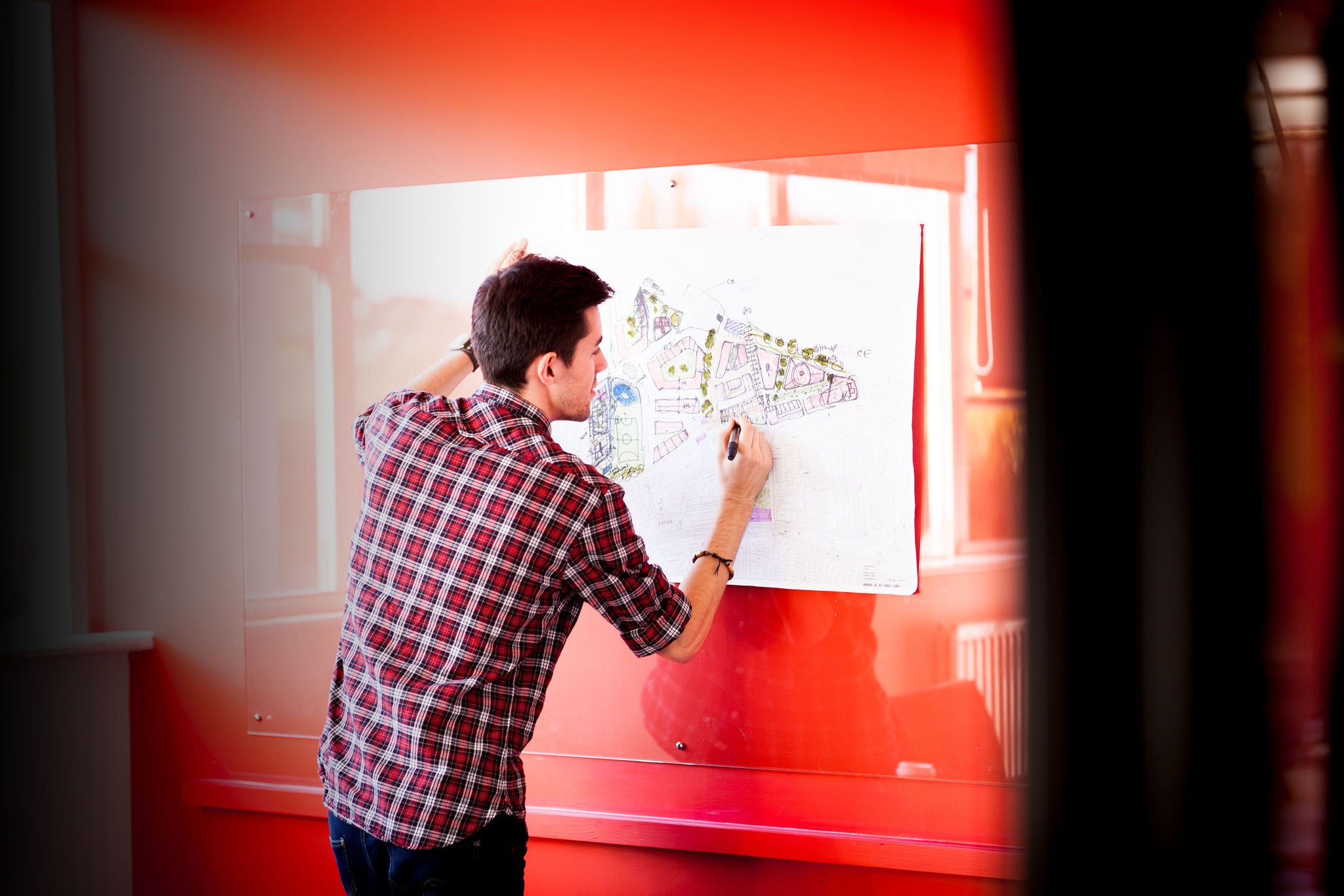 young male architect i his studio, working on an architectural drawing