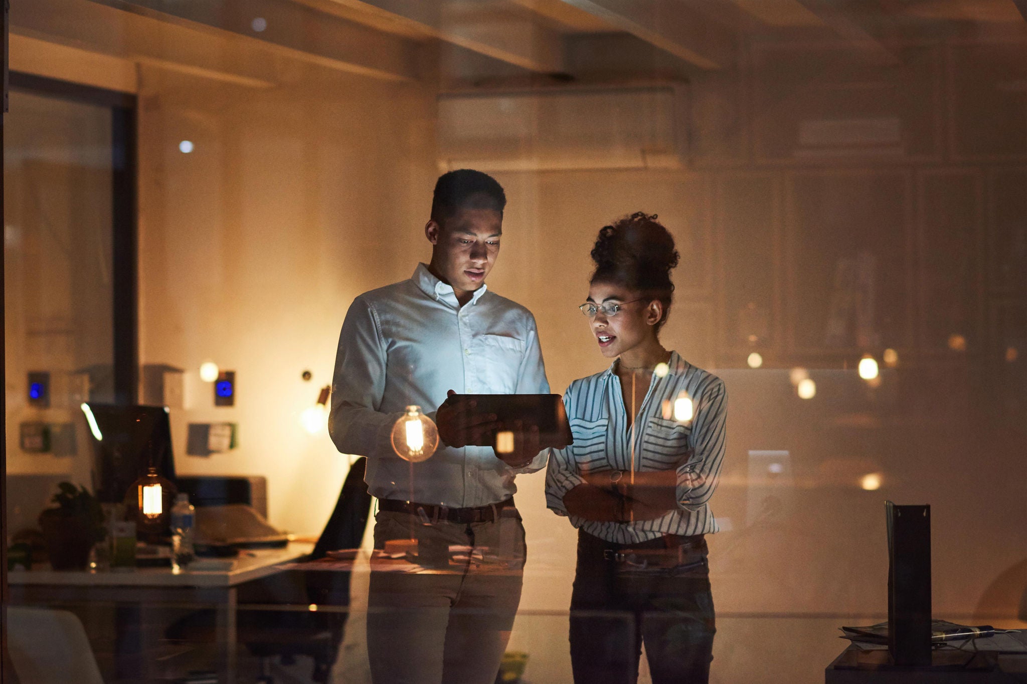 Shot of a young businessman and businesswoman using a digital tablet during a late night at work