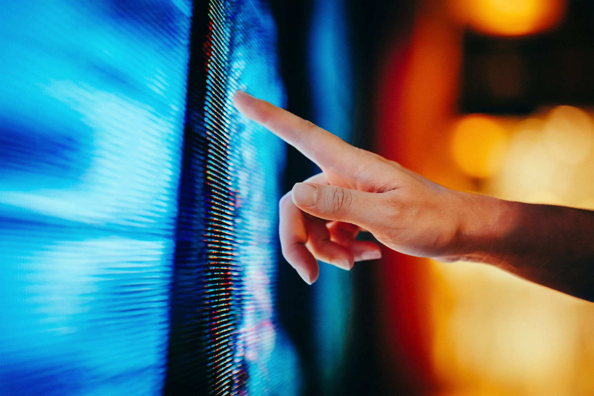 Close up of hand touching illuminated and multicoloured LED display screen