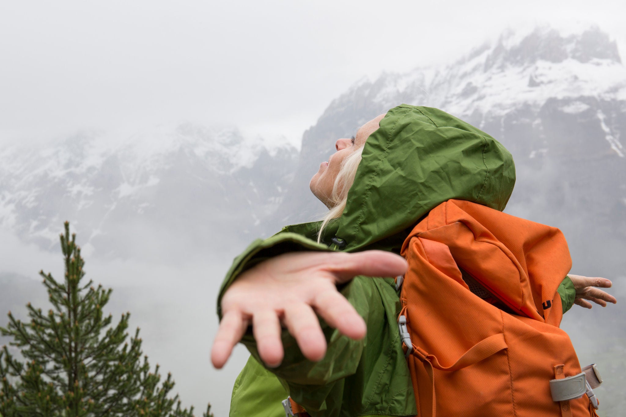 Female hiker spreads arms to embrace mountain mist