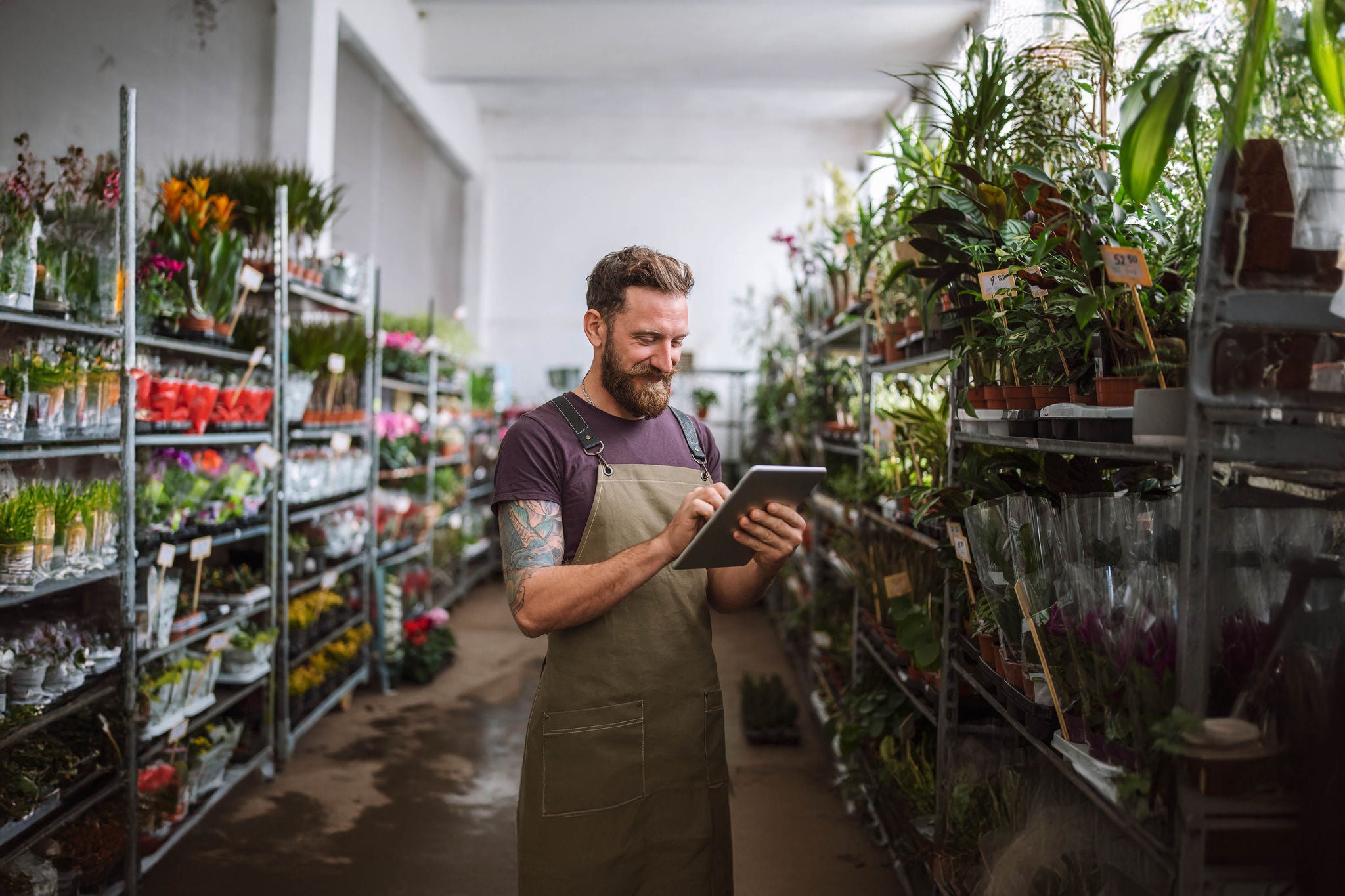 Male worker in florist shop using digital tablet