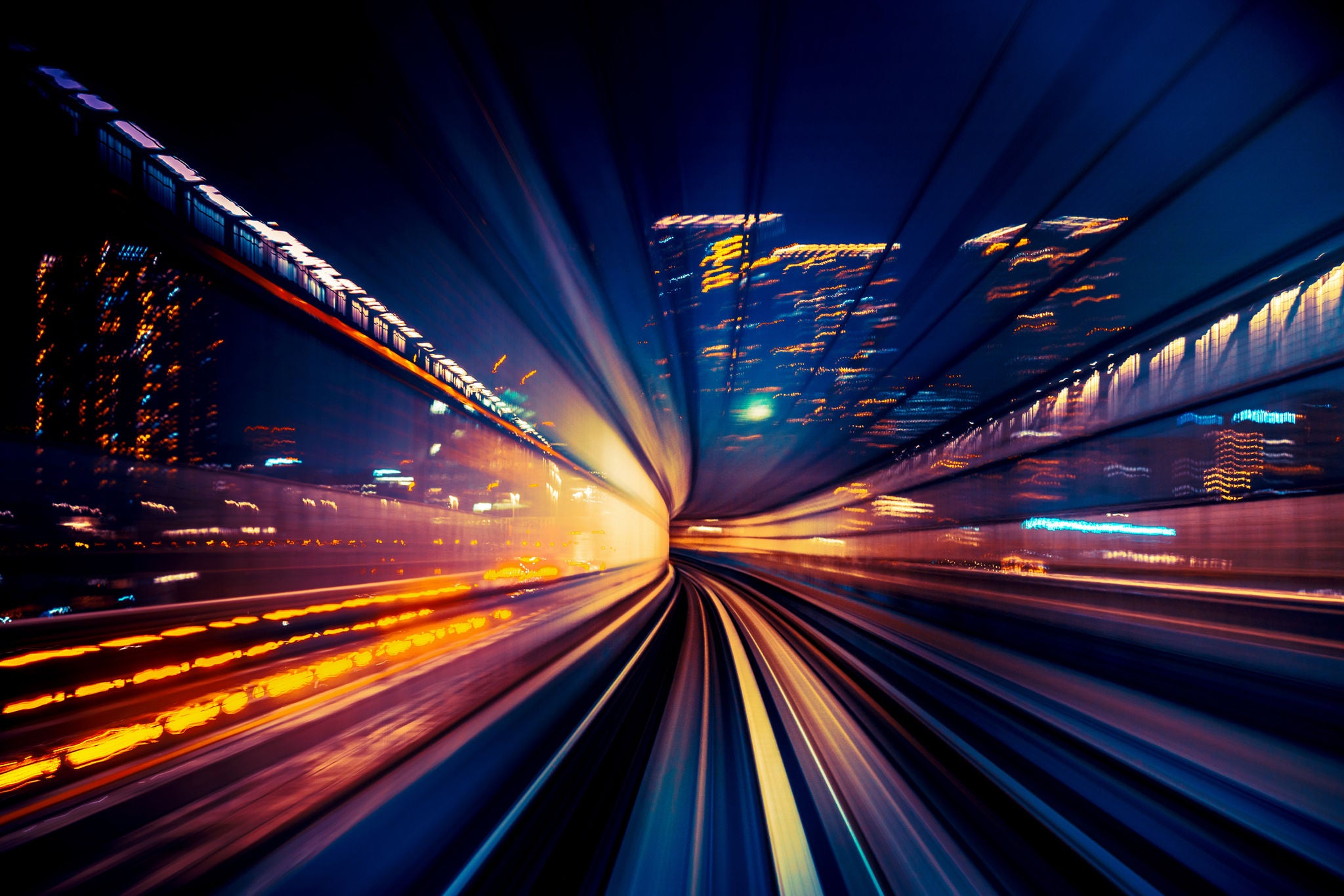 High speed train driving along the rails through a train station tunnel at night.
Motion Blur and  Long Exposure