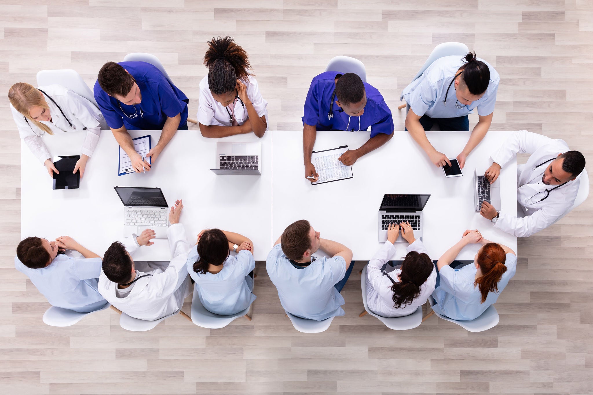 Positive Young Specialists With Stethoscope Having Discussion Of Research Work In Conference Room