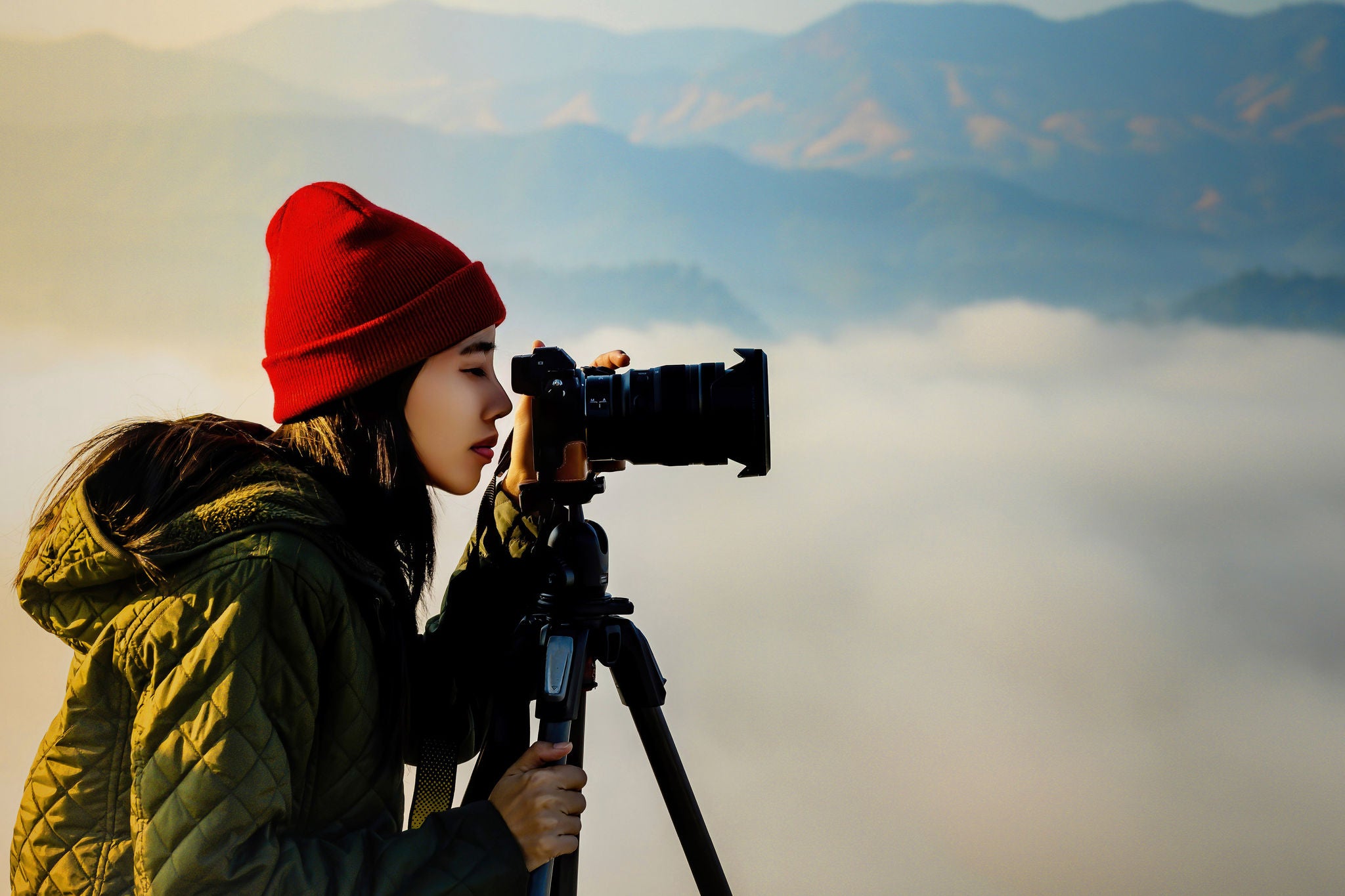 A woman takes a photo with misty mountains in the background.