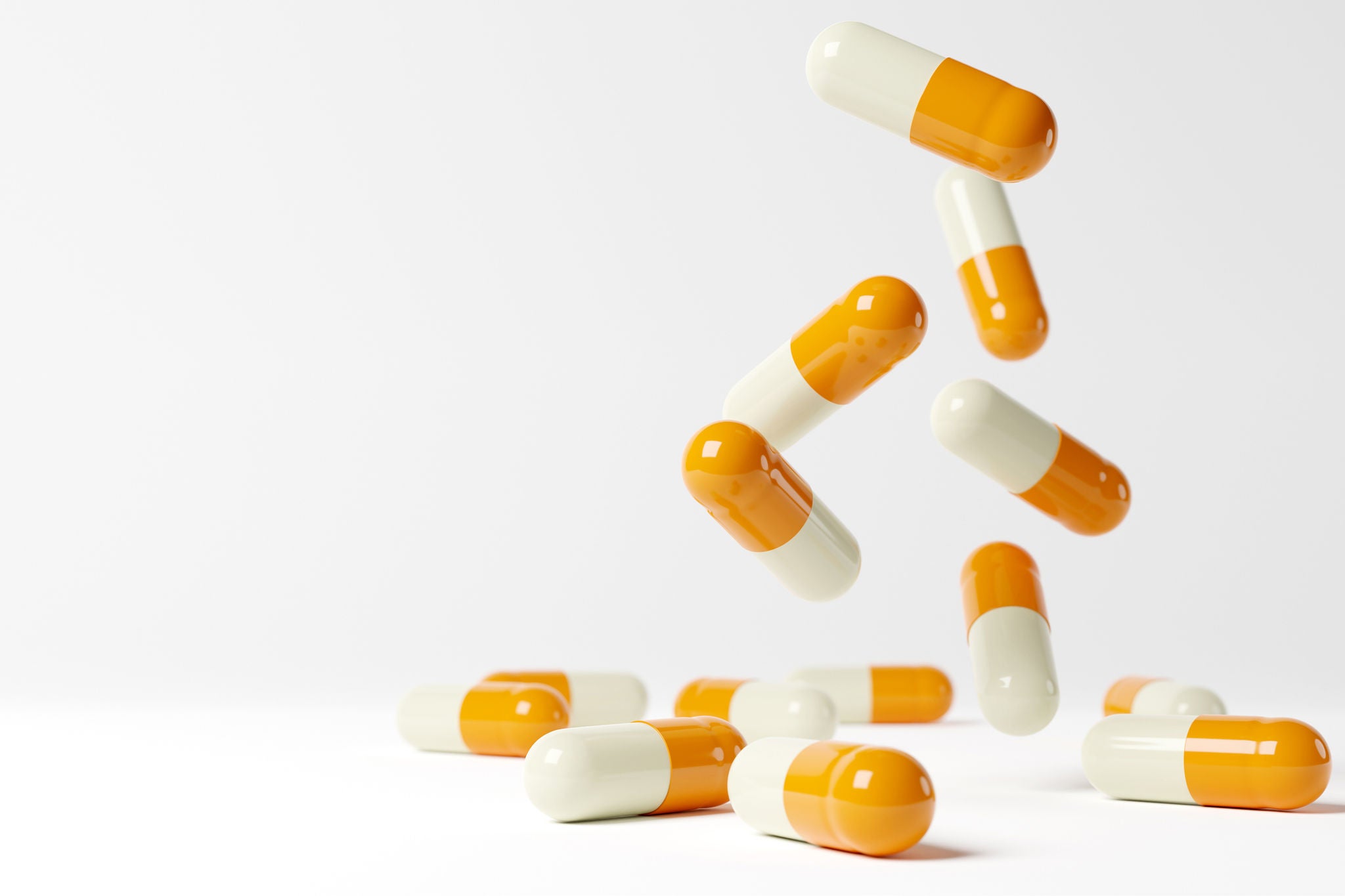 Yellow and white medical capsules falling down on the blue background. 3D render. 3D illustration.