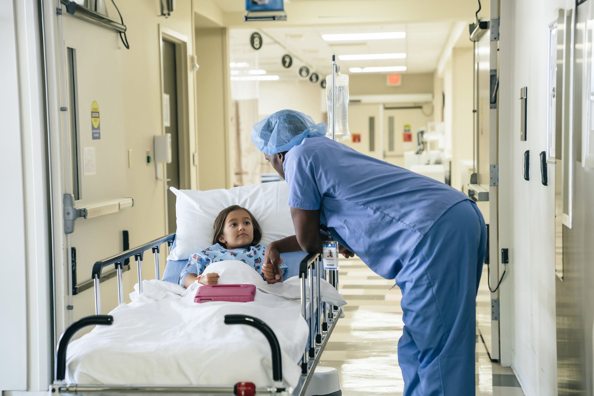 Doctor holding hand of girl in hospital gurney