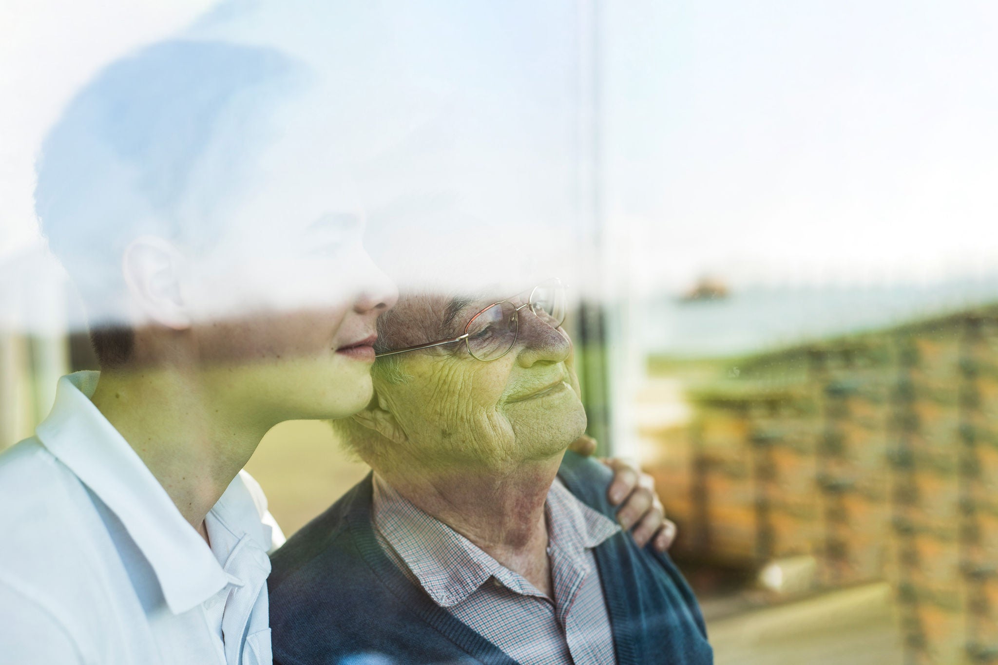 Male nursestanding by the window with elderly man