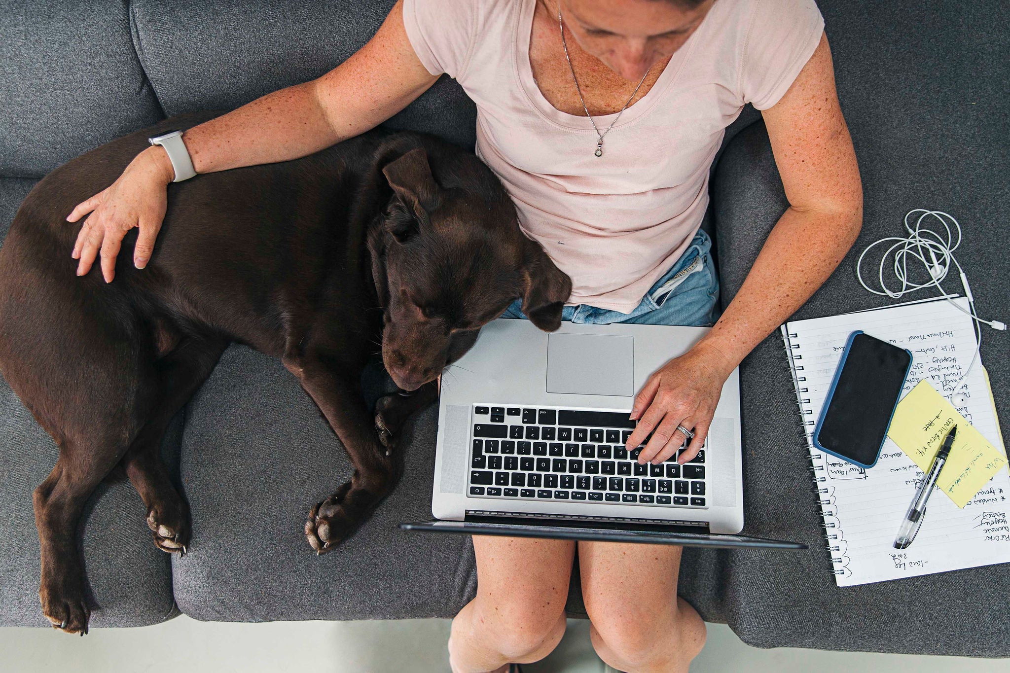 Woman working from home. Her pet dog lies asleep next to her