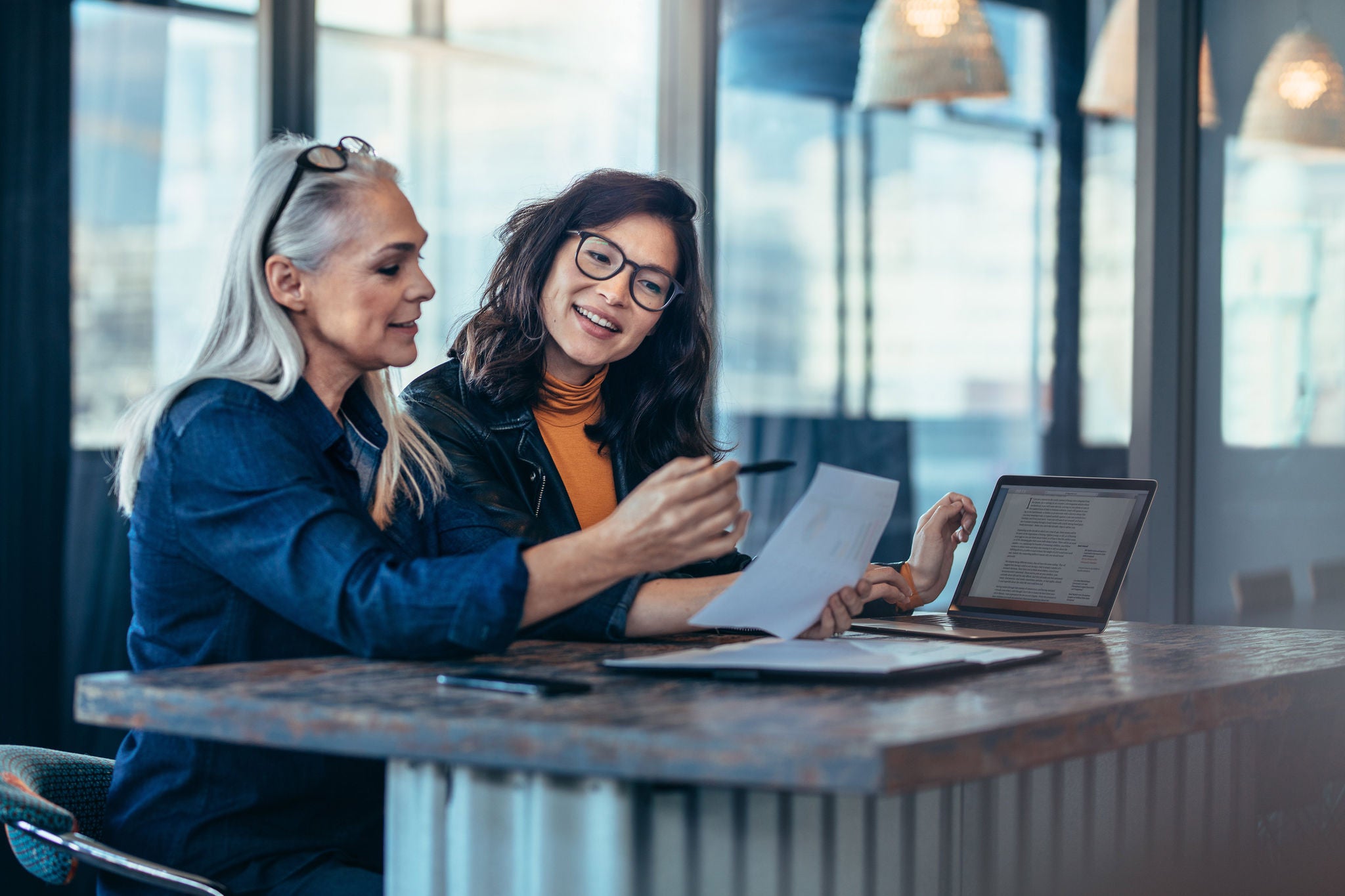 EY two women discuss documents in office