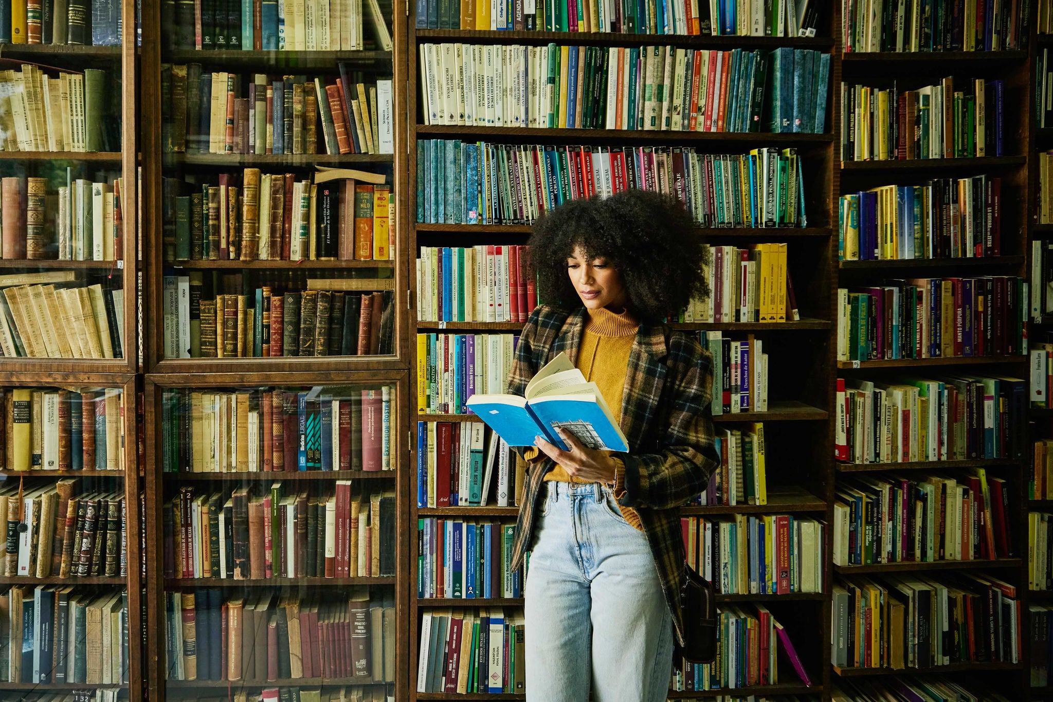 Woman reading book while browsing in antique bookstore