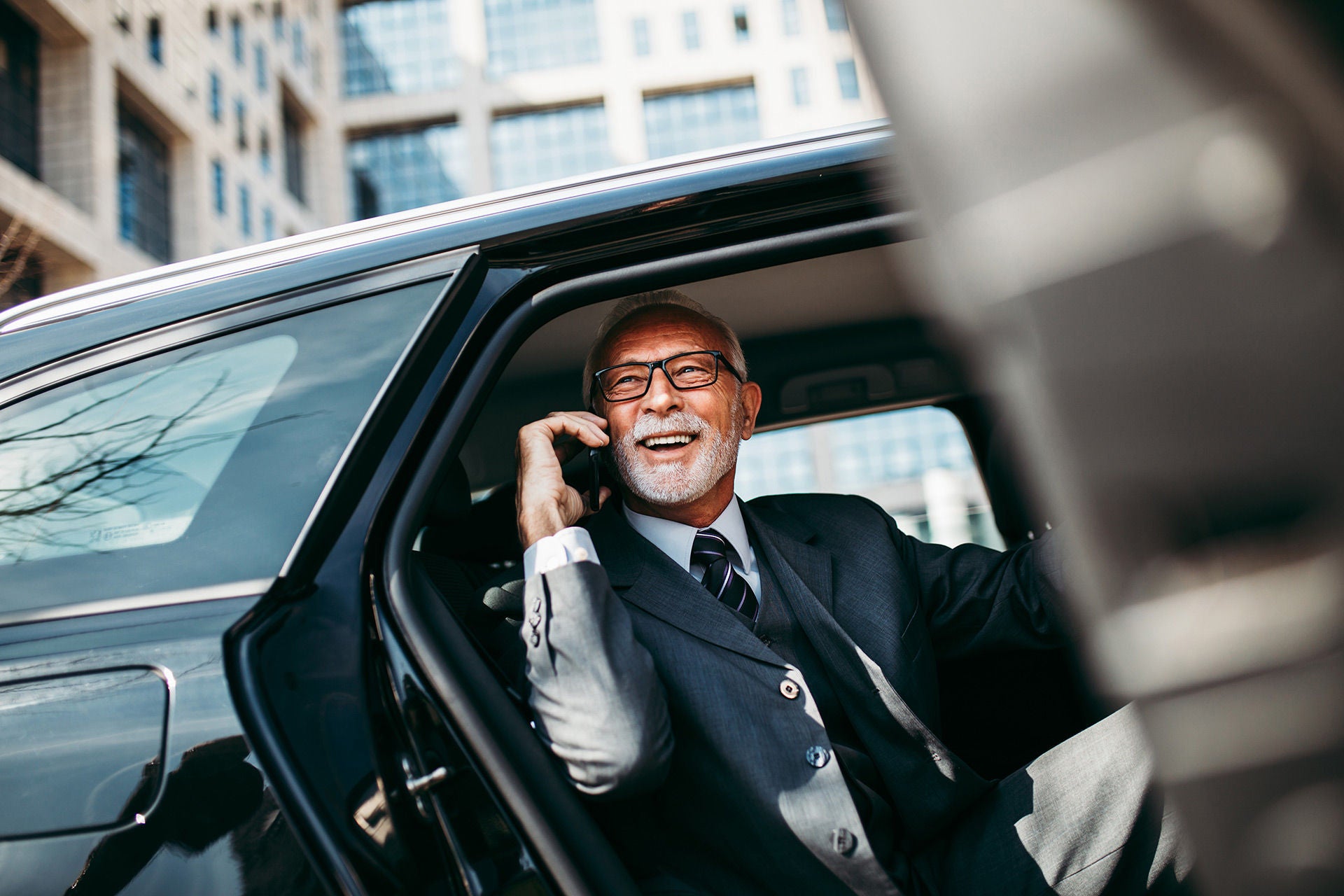 good looking senior business man sitting on backseat in luxury car