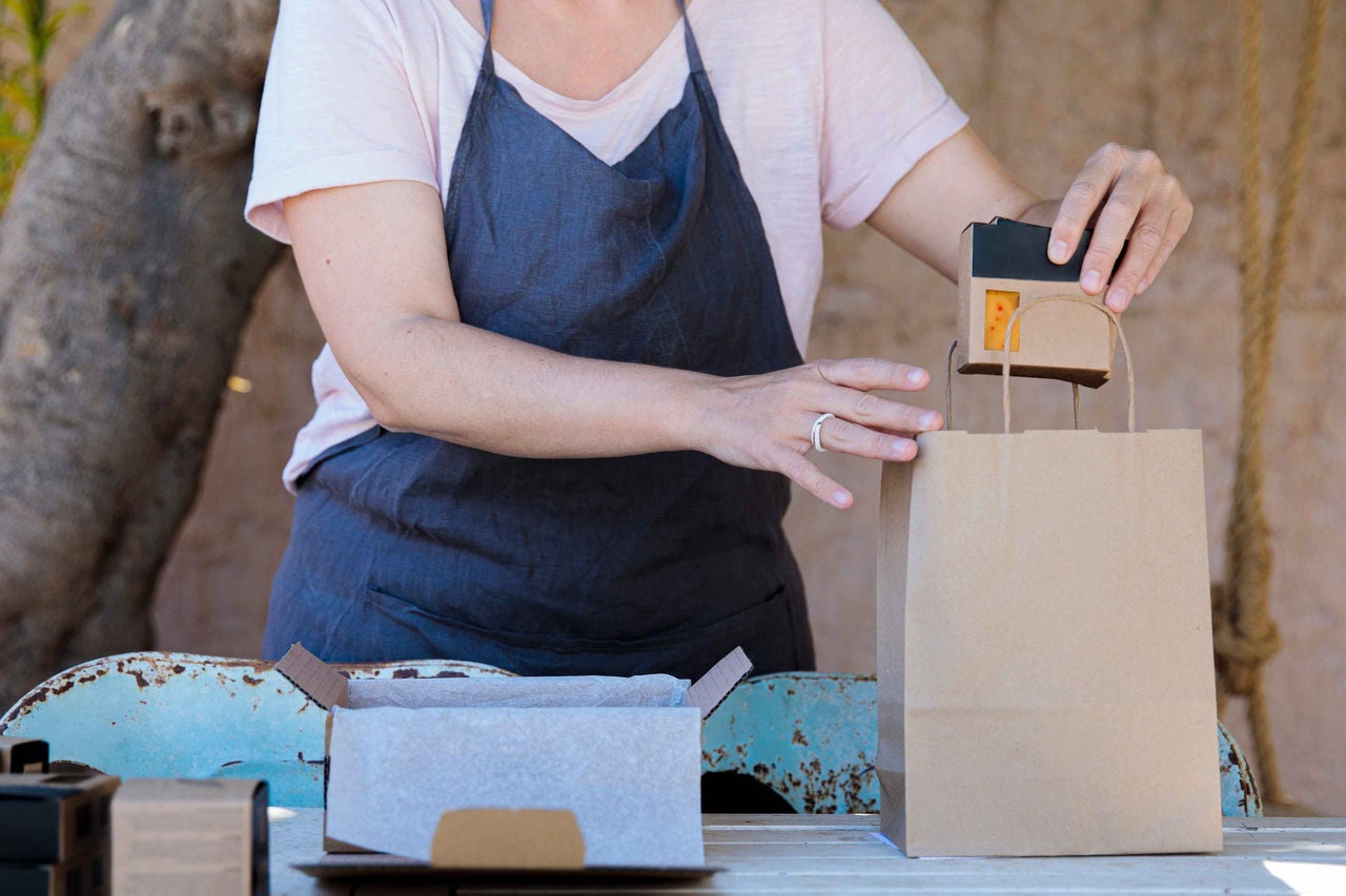 Frau bereitet wiederverwendbare Geschenkverpackungen aus Karton auf dem Tisch vor