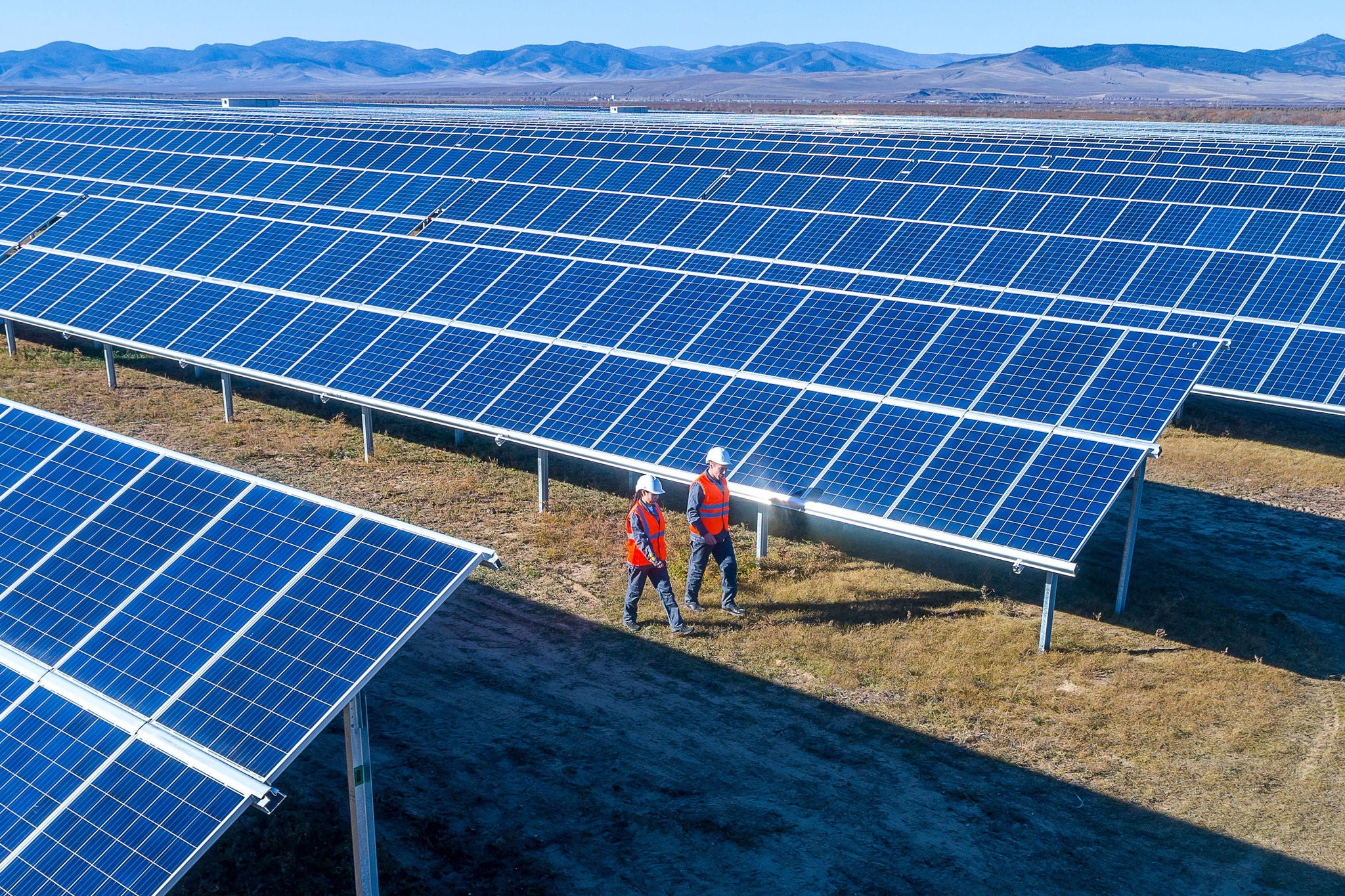 Ywo people walking near solar panels