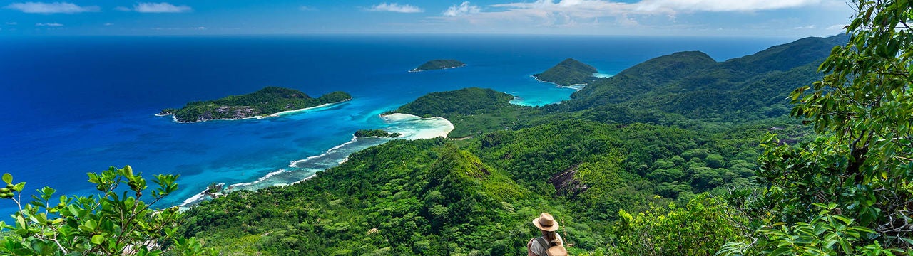 female hiker woman tourist standing high above indian ocean on tropical island of seychelles mahe enjoying amazing view
