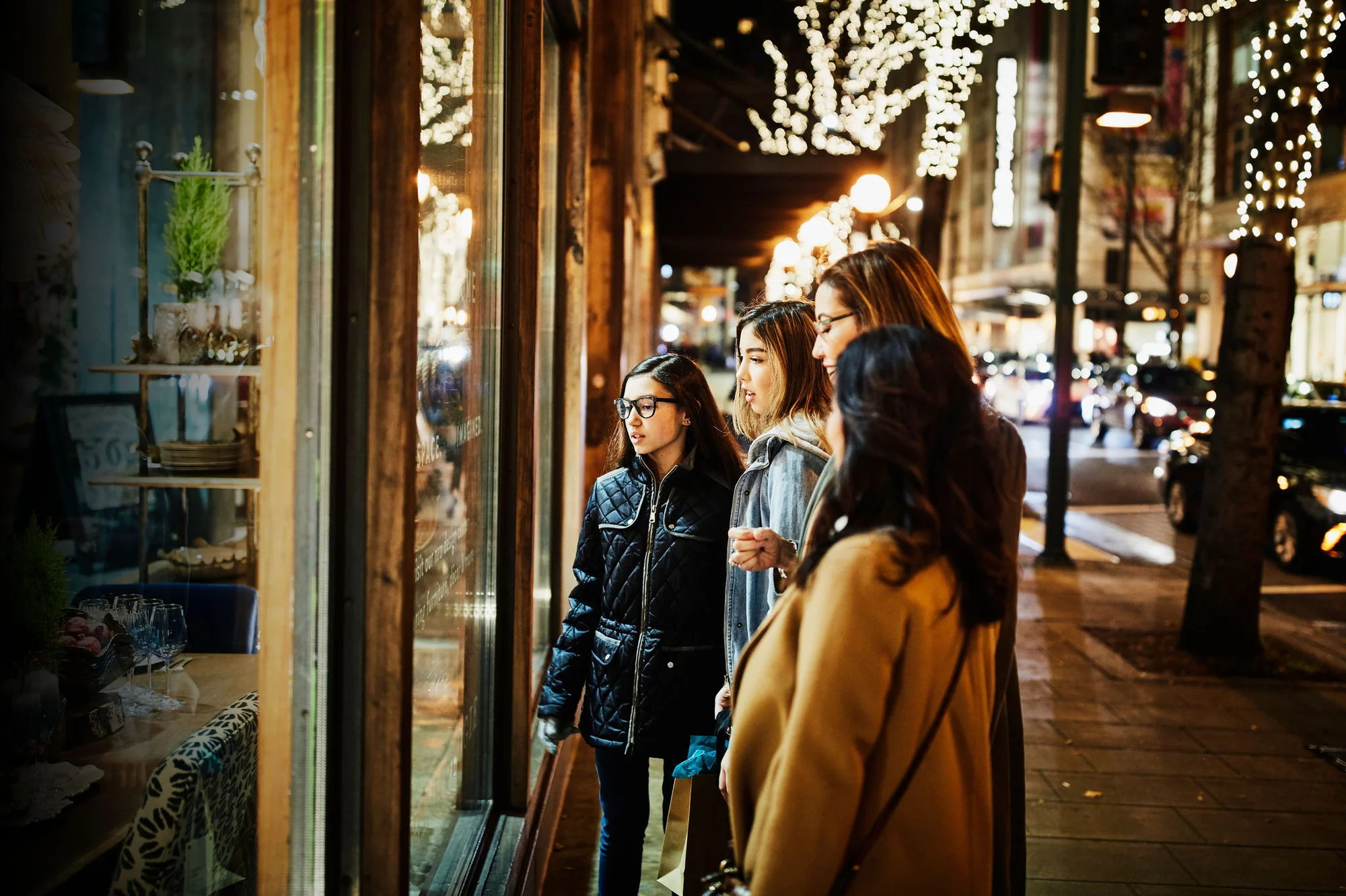 Two mature women and teenage daughters window shopping during holidays